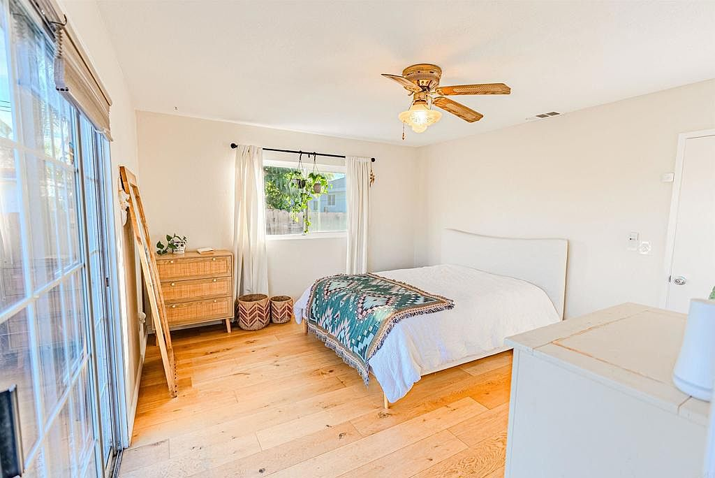 Primary bedroom wide-angle with hardwood floors and natural light