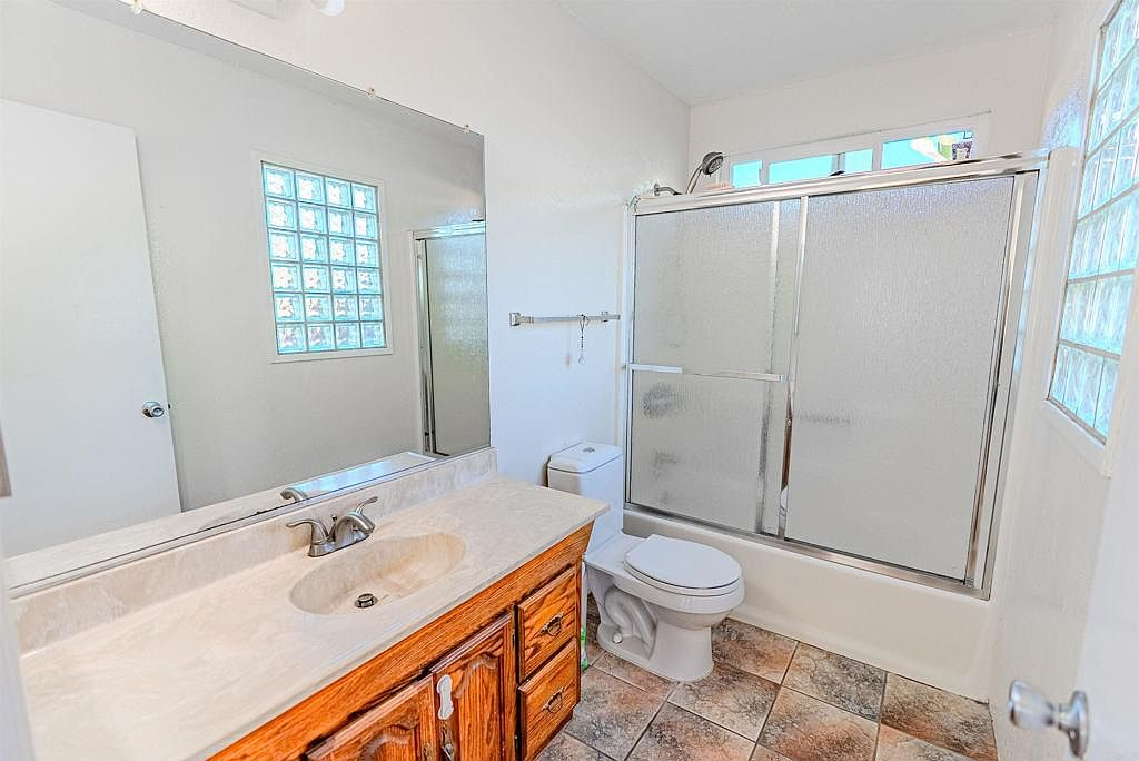 Bathroom with vanity, marble countertop, and glass block windows