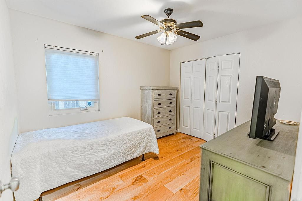 Secondary bedroom with warm hardwood floors and white bifold closet