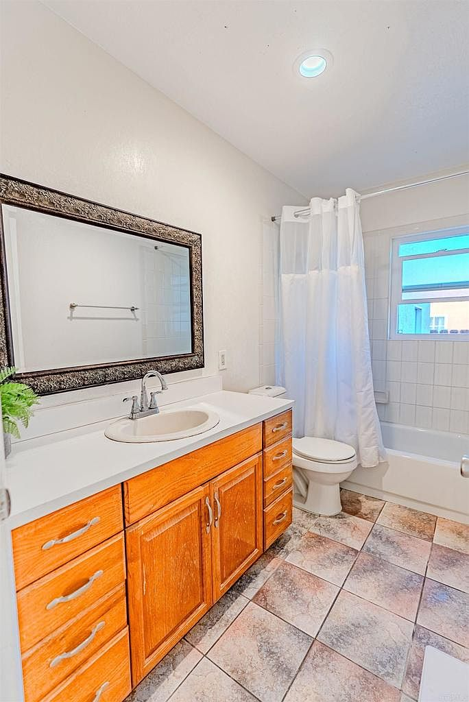 Updated bathroom with honey oak vanity and tiled tub surround
