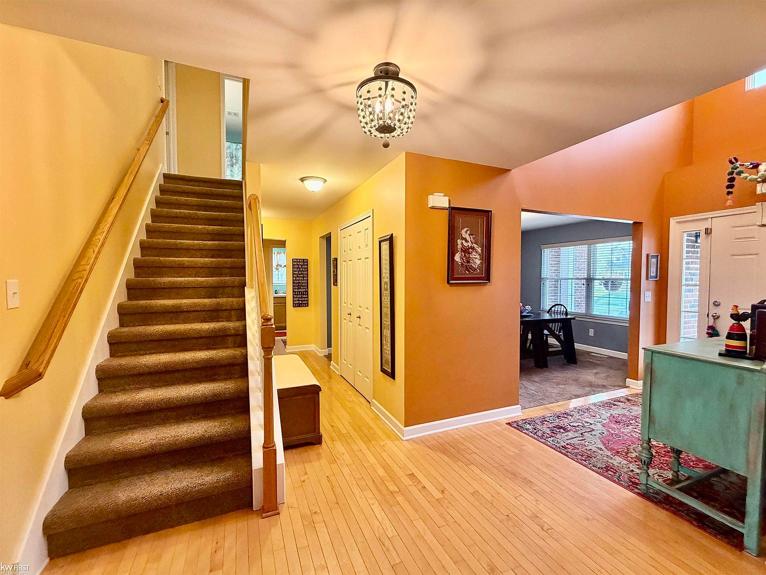 Foyer entryway with carpeted staircase and crystal chandelier