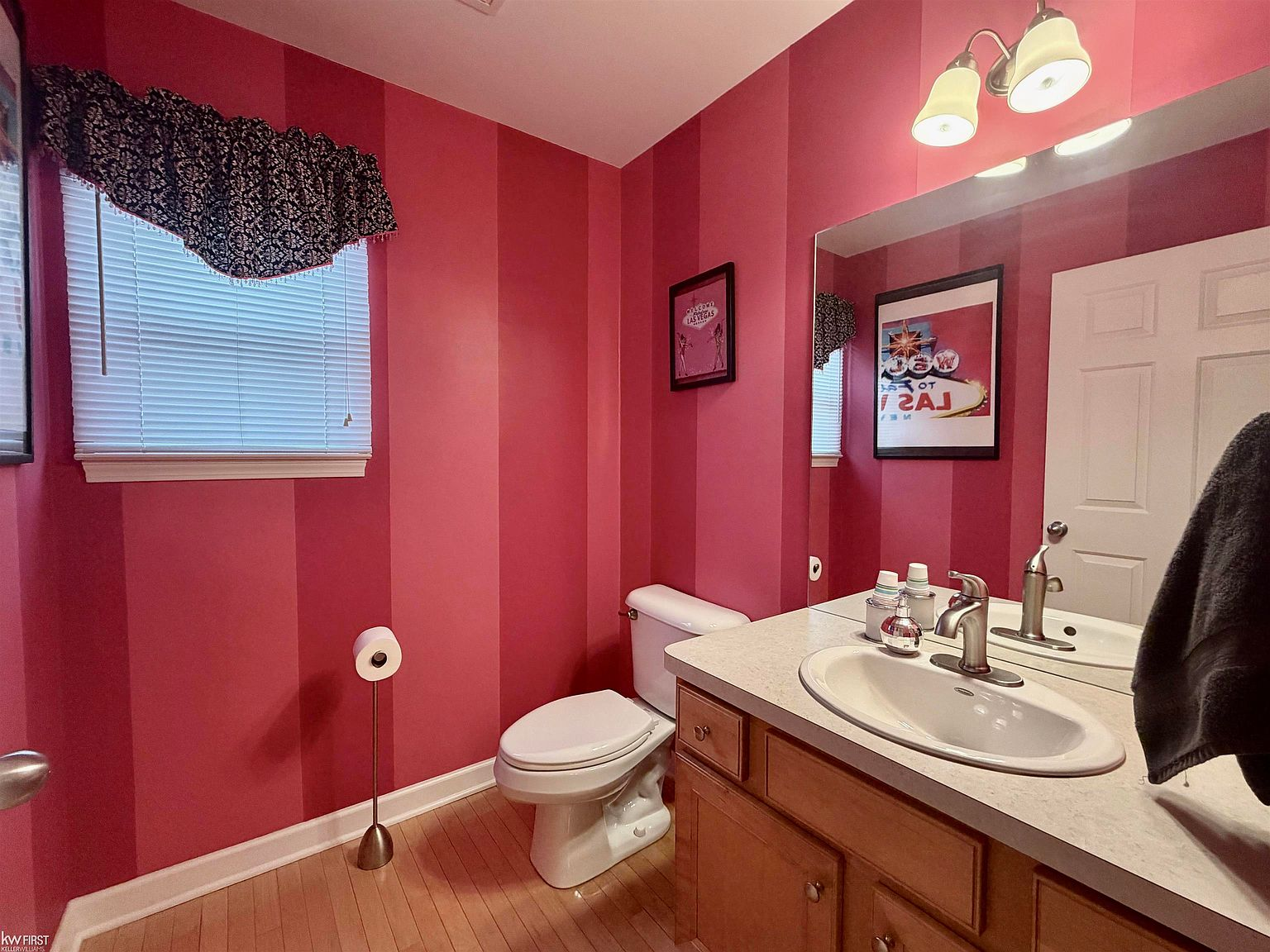 Powder room with bold pink striped wallpaper