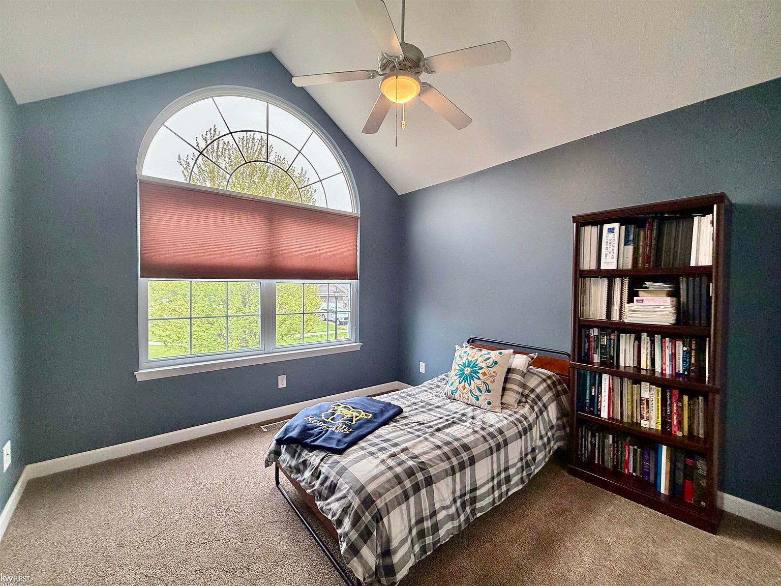 Bedroom with high vaulted ceiling and round arch window