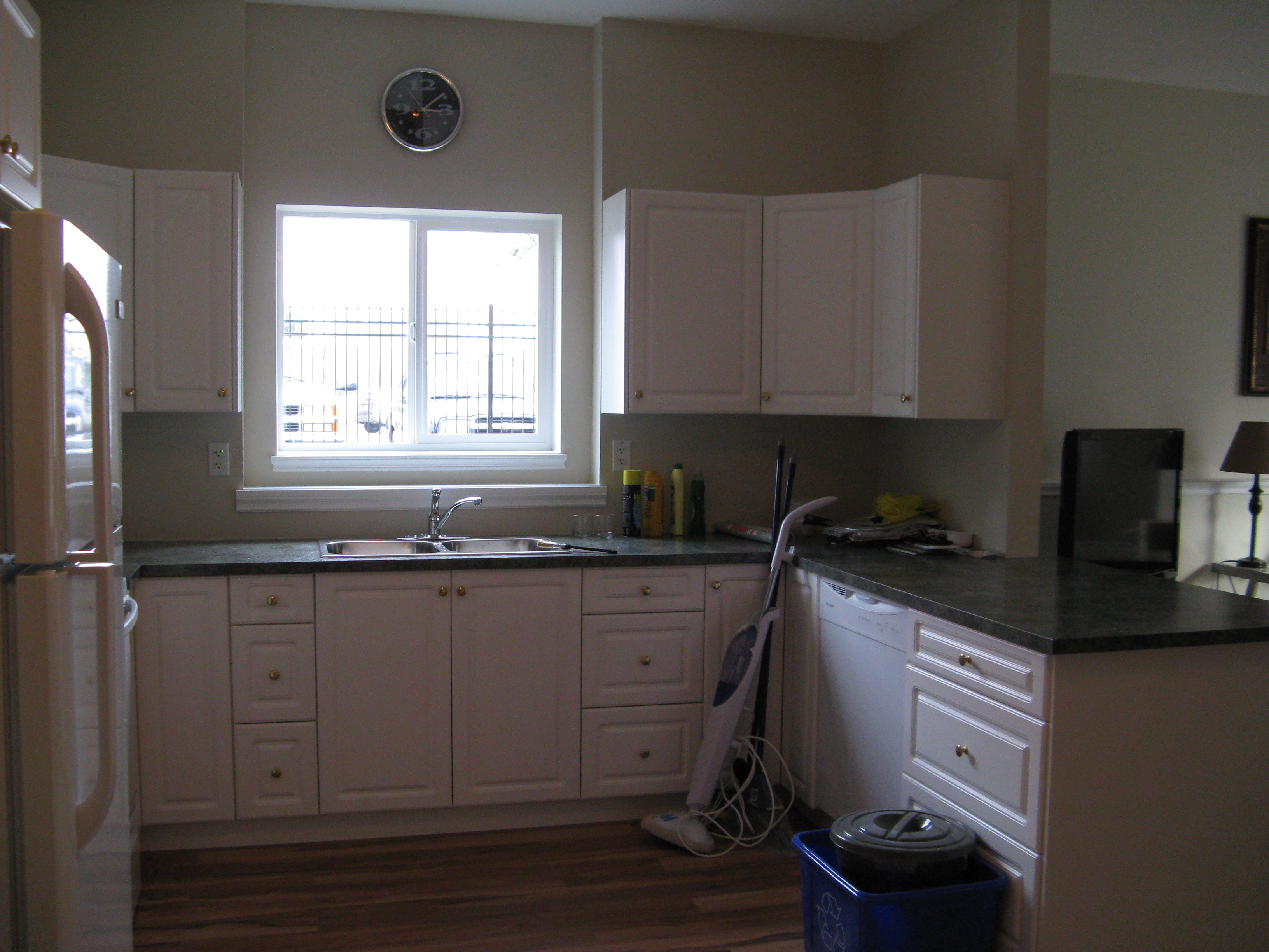Kitchen sink area with white shaker cabinets and dark laminate countertops