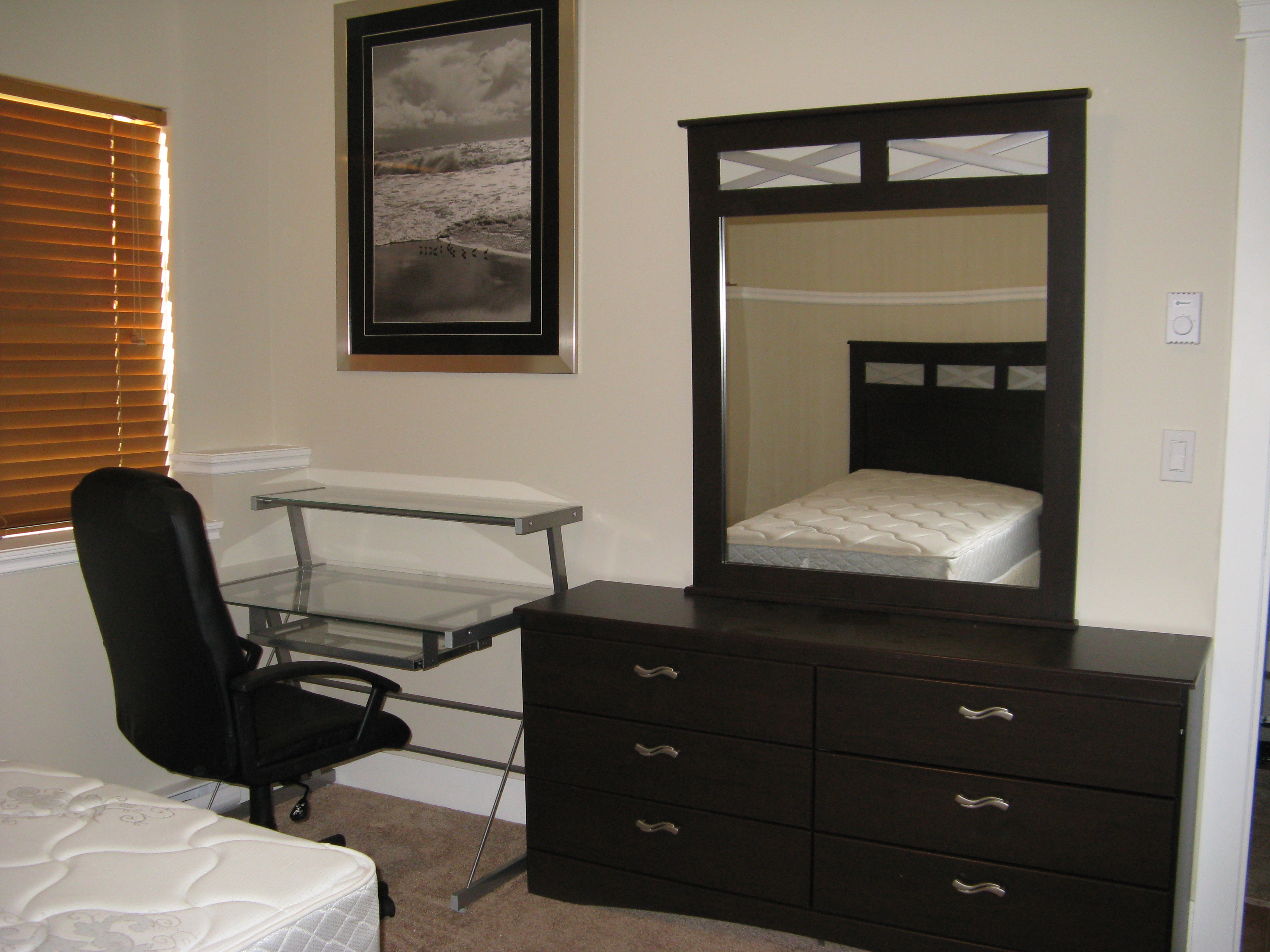 Bedroom with dark wood dresser, mirror, and desk workspace