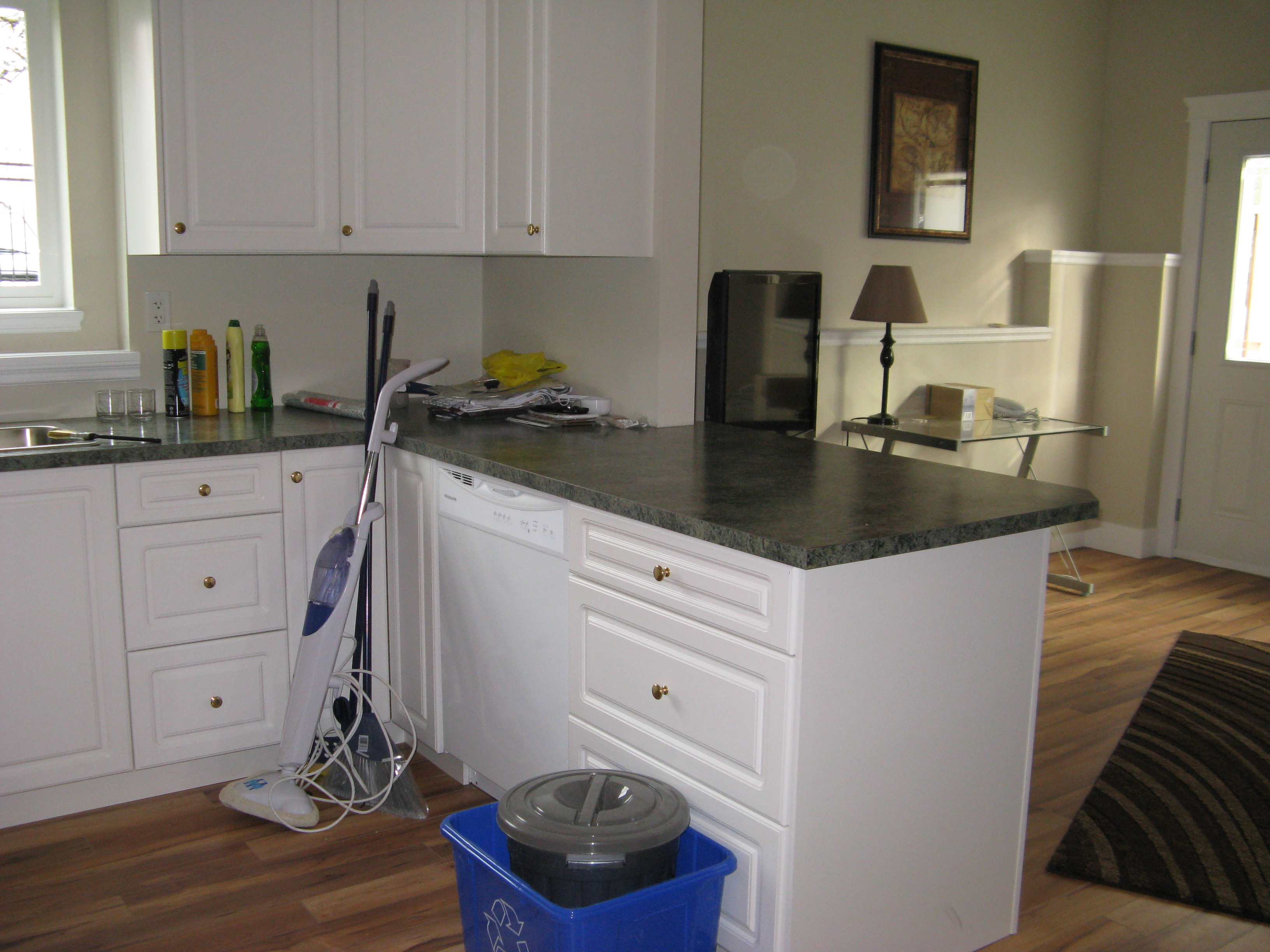 Kitchen peninsula with white shaker cabinets and dark grey laminate countertops