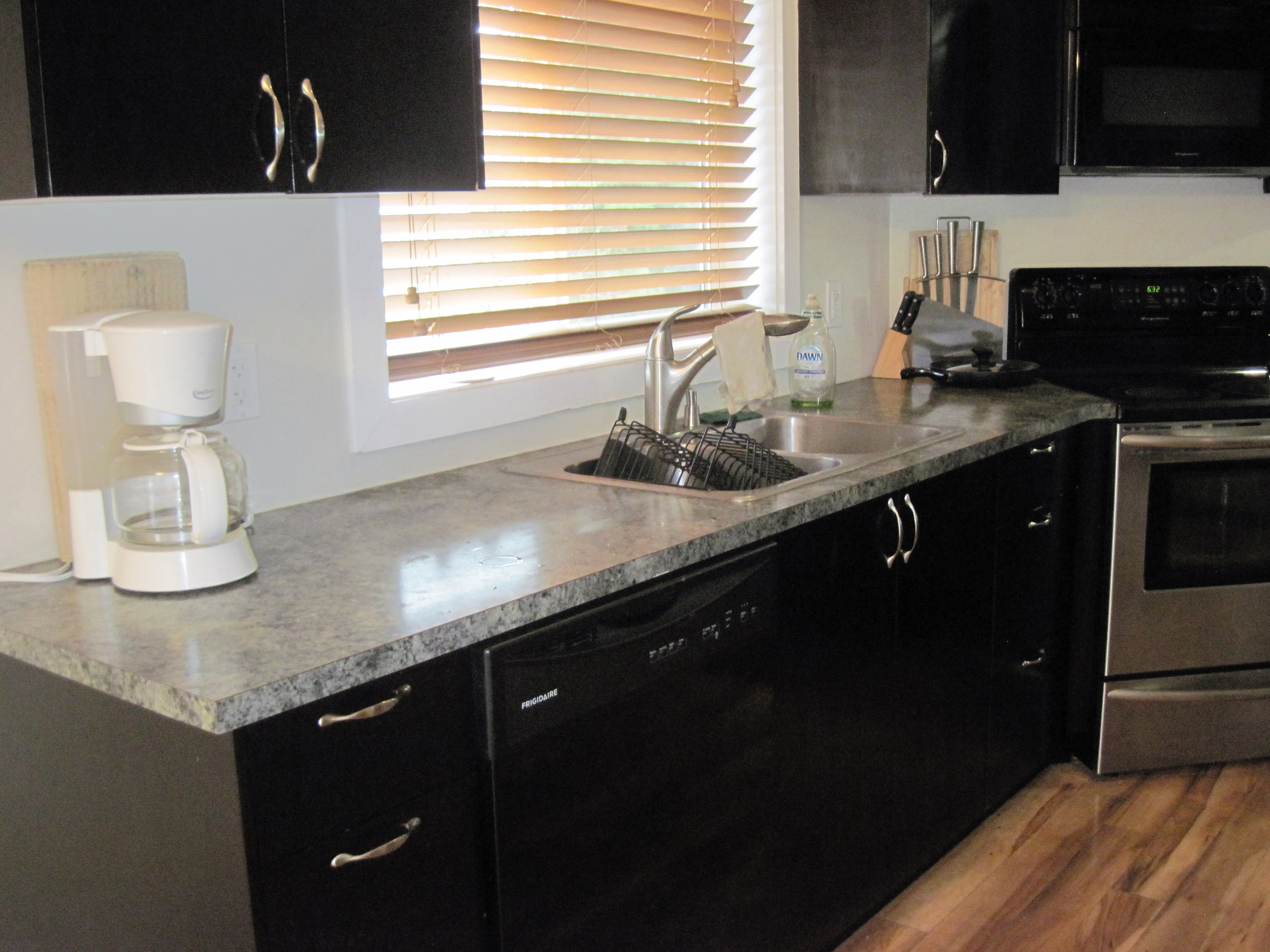 Kitchen sink and countertop area with glossy flat-panel black cabinets