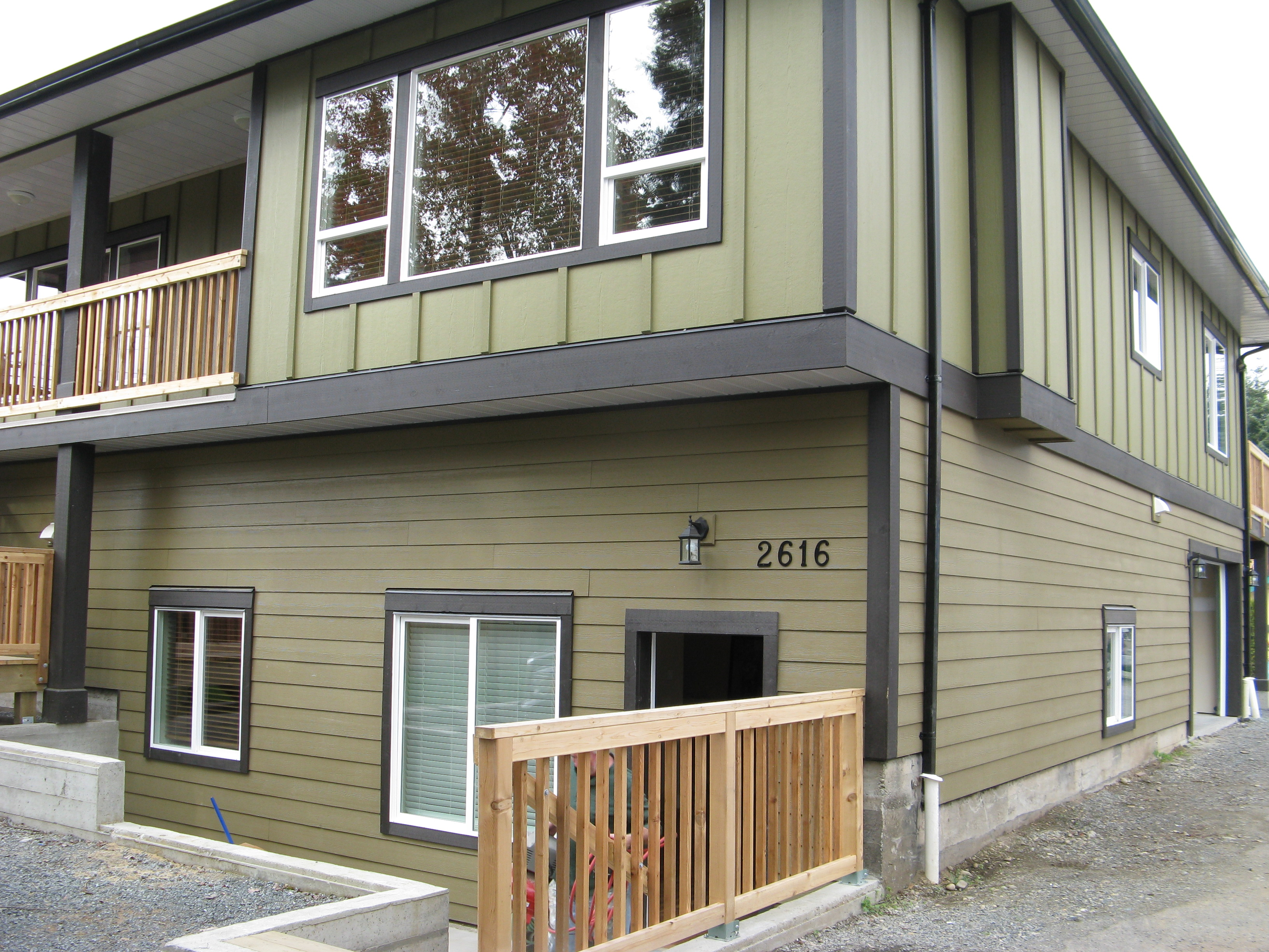 Side angle of the two-story home with sage green siding and dark trim