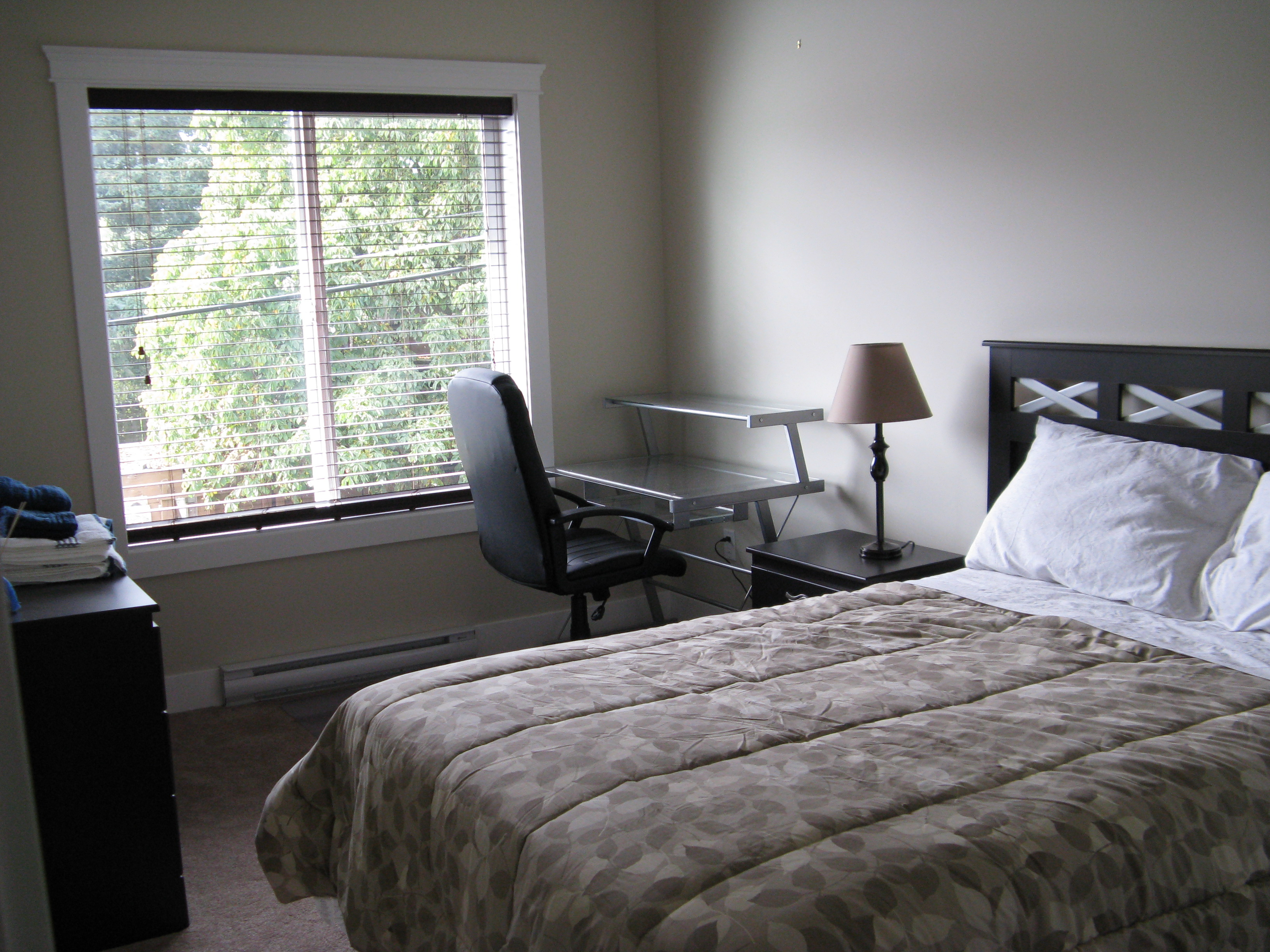 Secondary bedroom with bed frame, nightstand, and desk workspace