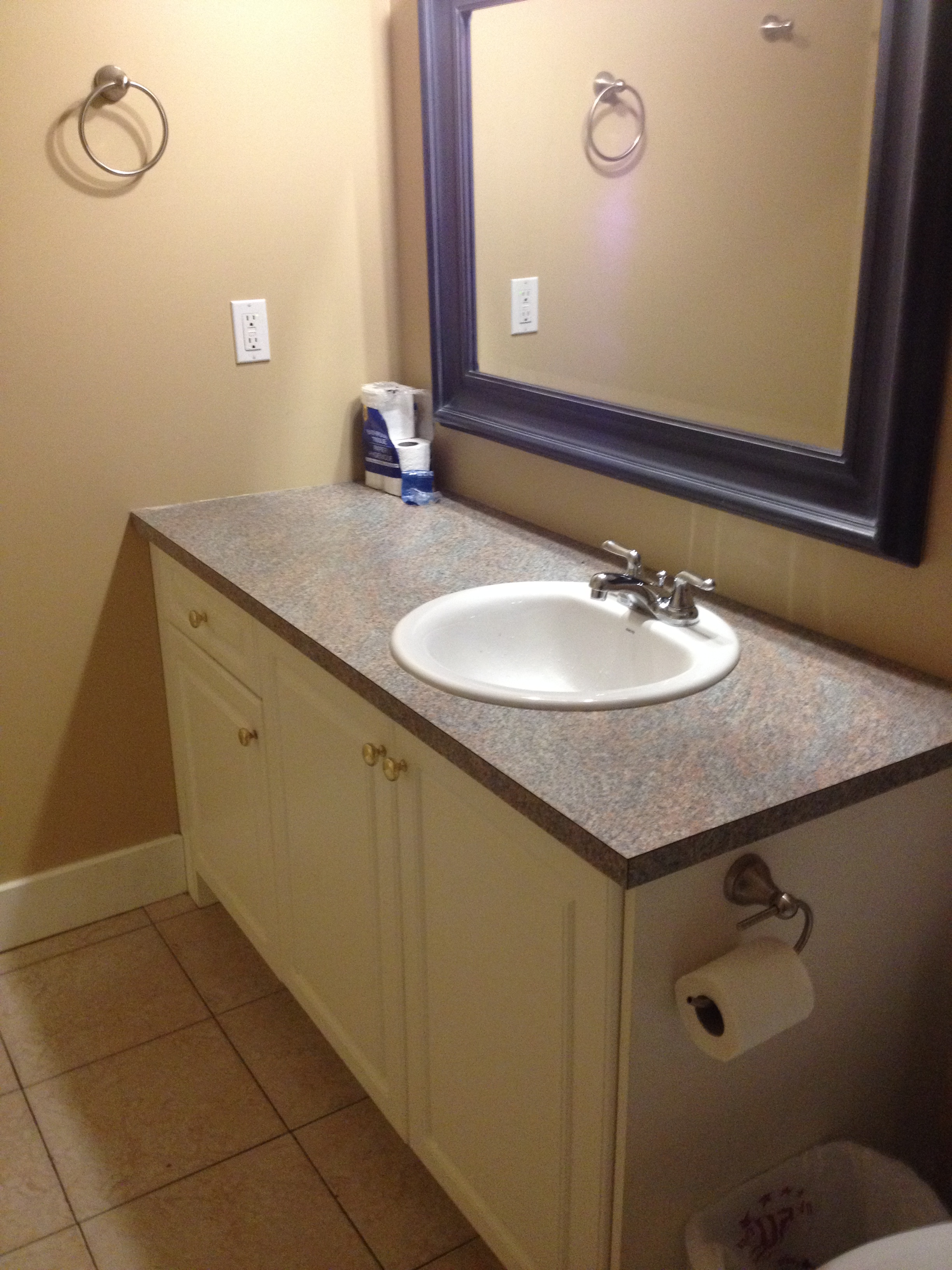 Bathroom vanity with cream-colored cabinets and laminate faux-stone countertop