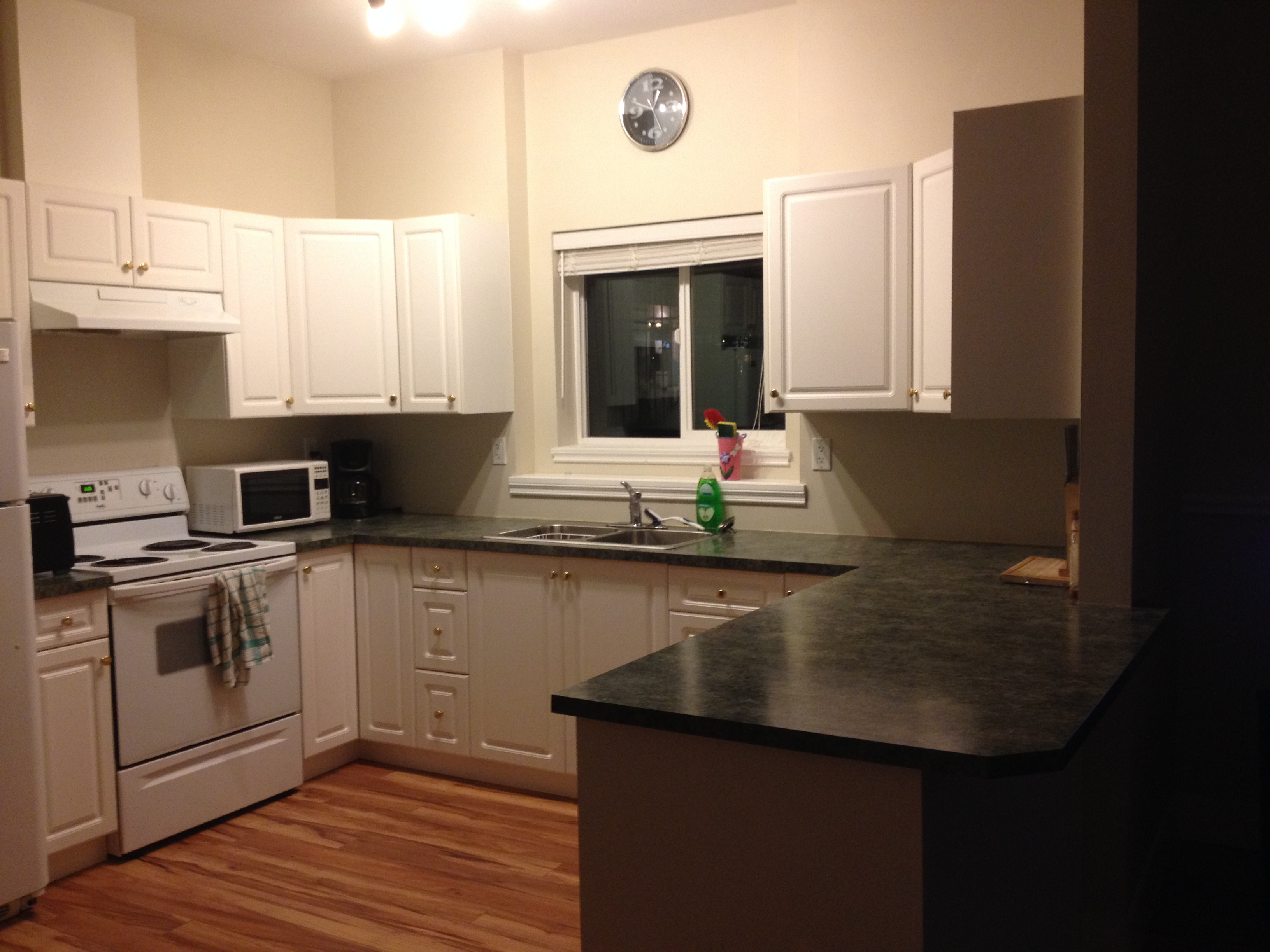 Kitchen with white raised-panel cabinetry and dark grey laminate countertops