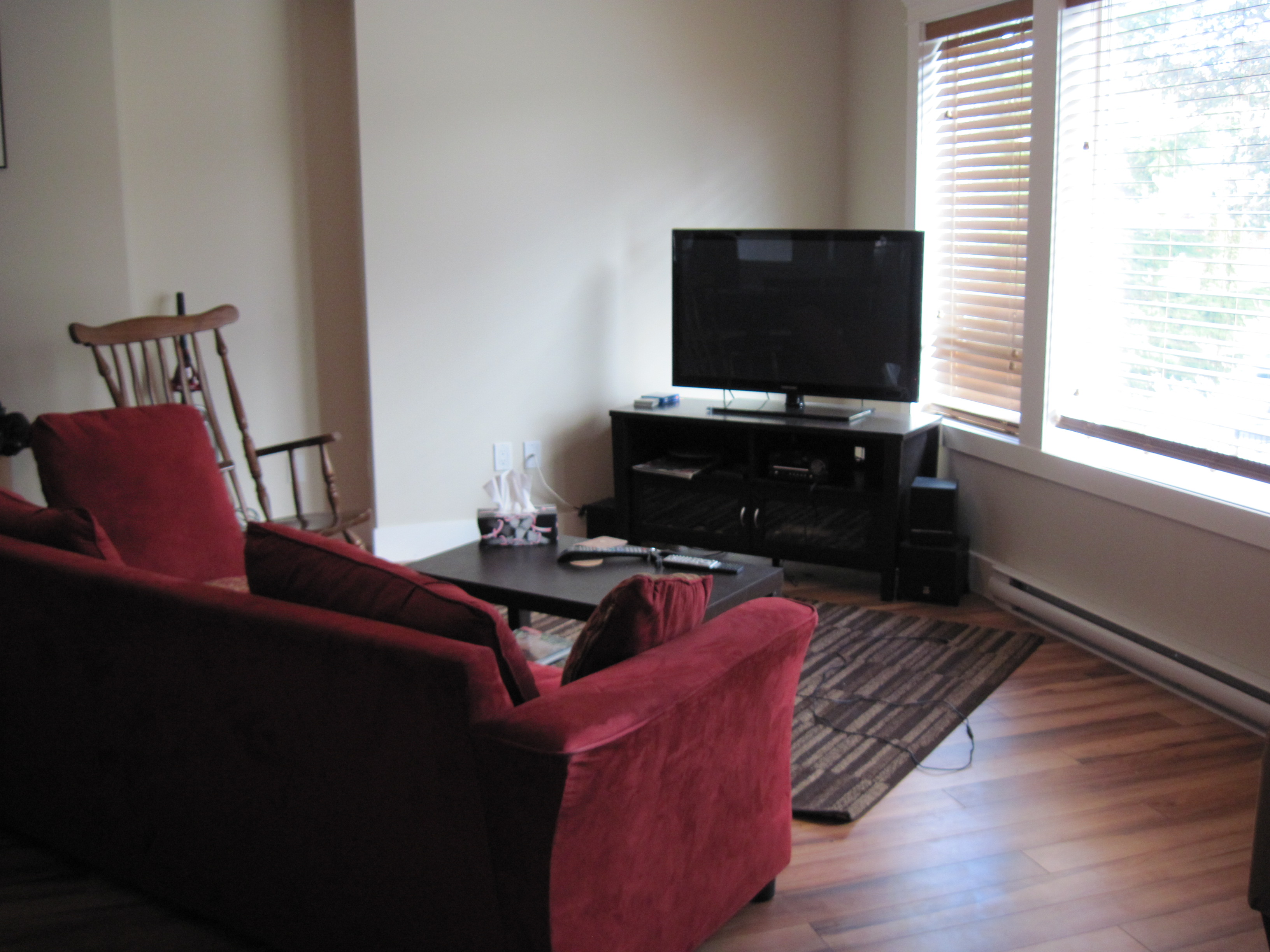 Living room with TV area and natural daylight through window blinds