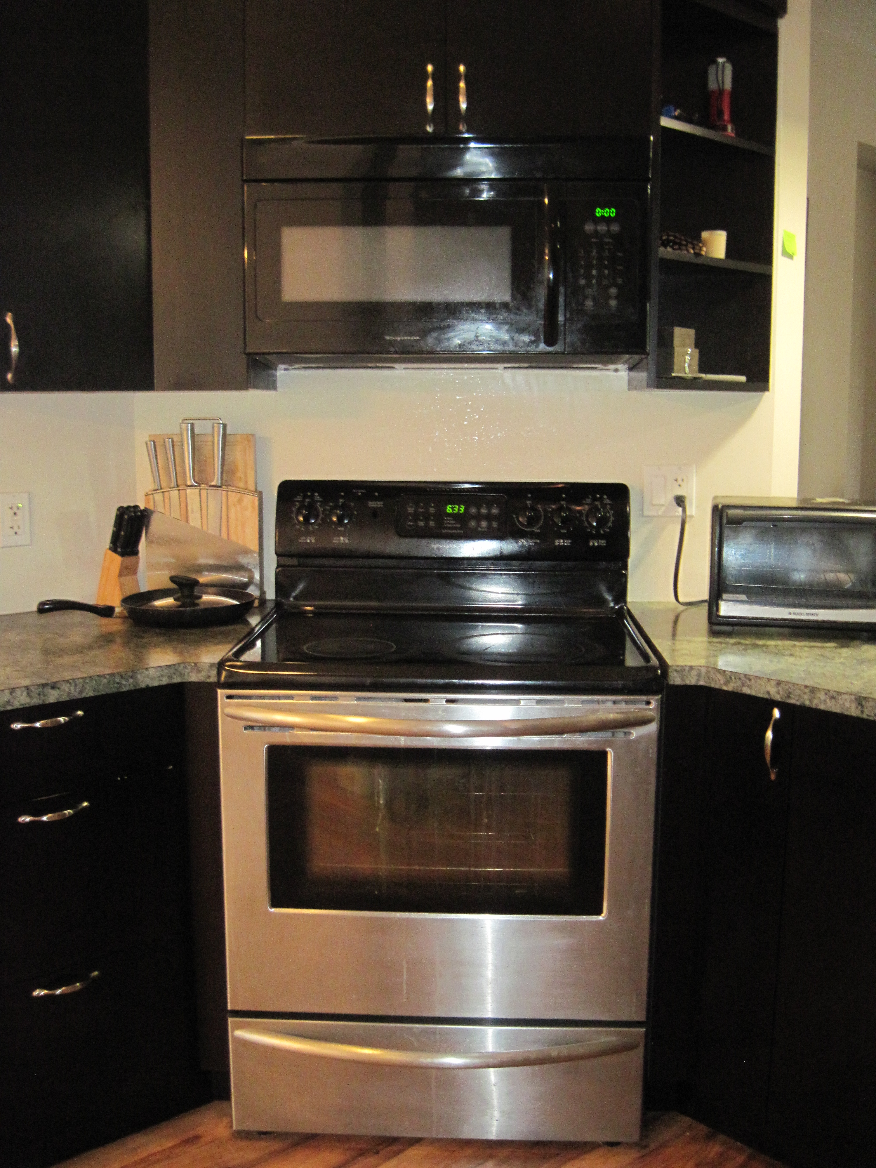 Kitchen cooking area with dark espresso cabinets and stainless steel appliances