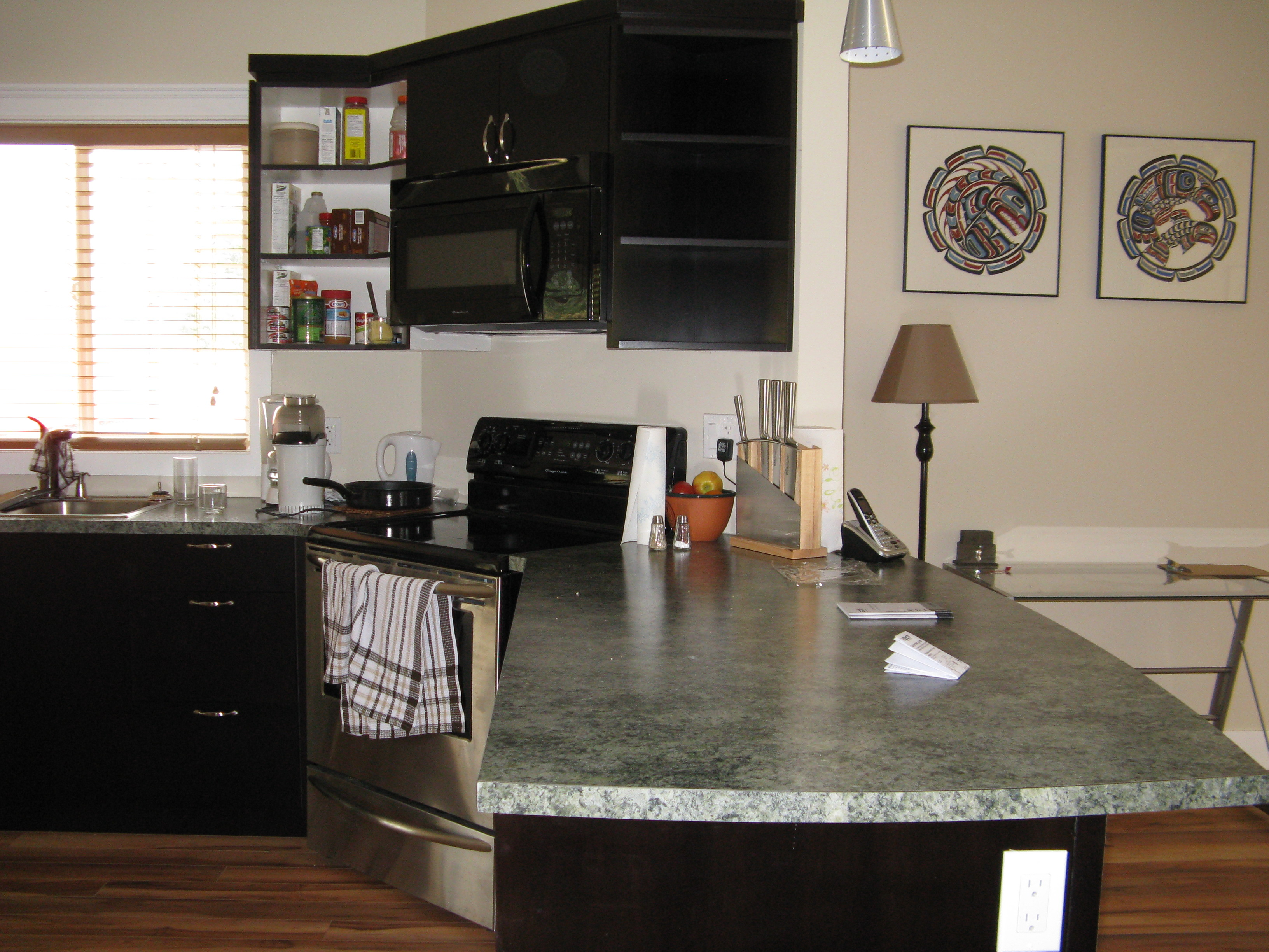 Kitchen peninsula and stove area with dark cabinetry and green-grey countertops