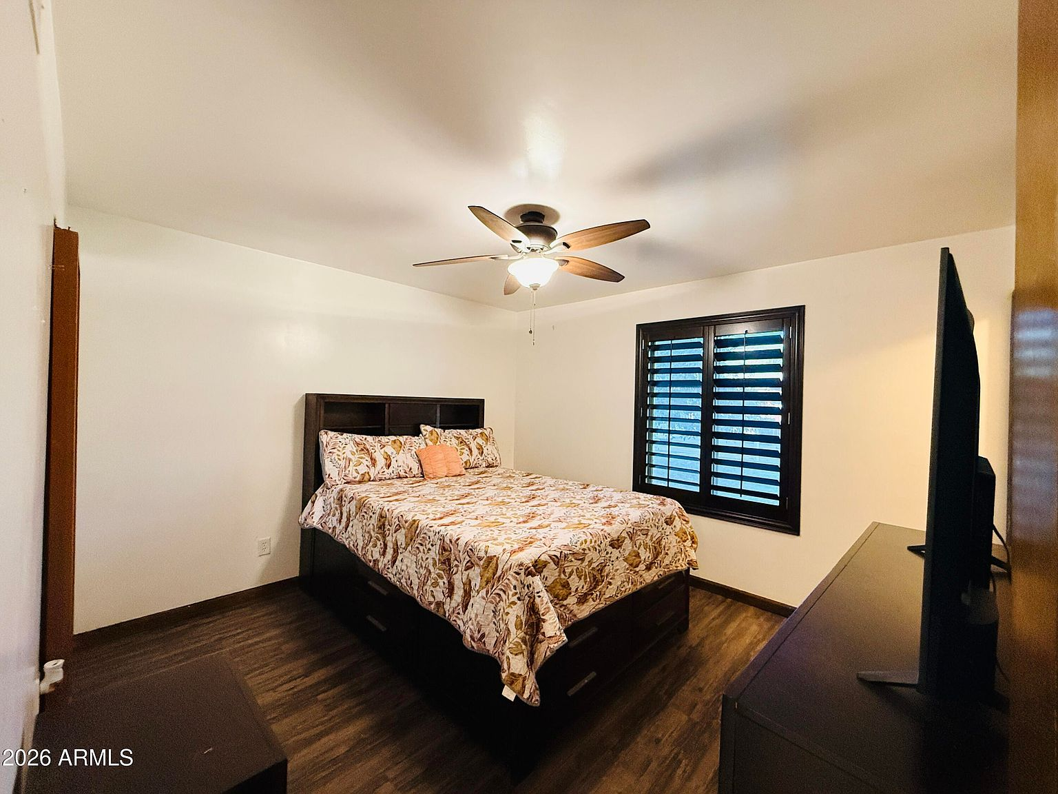 Bedroom with dark wood bed frame and plantation shutters