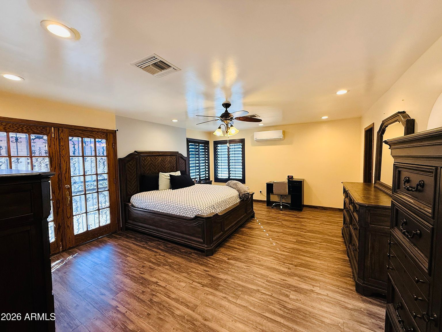 Master bedroom with wood-look flooring and French doors