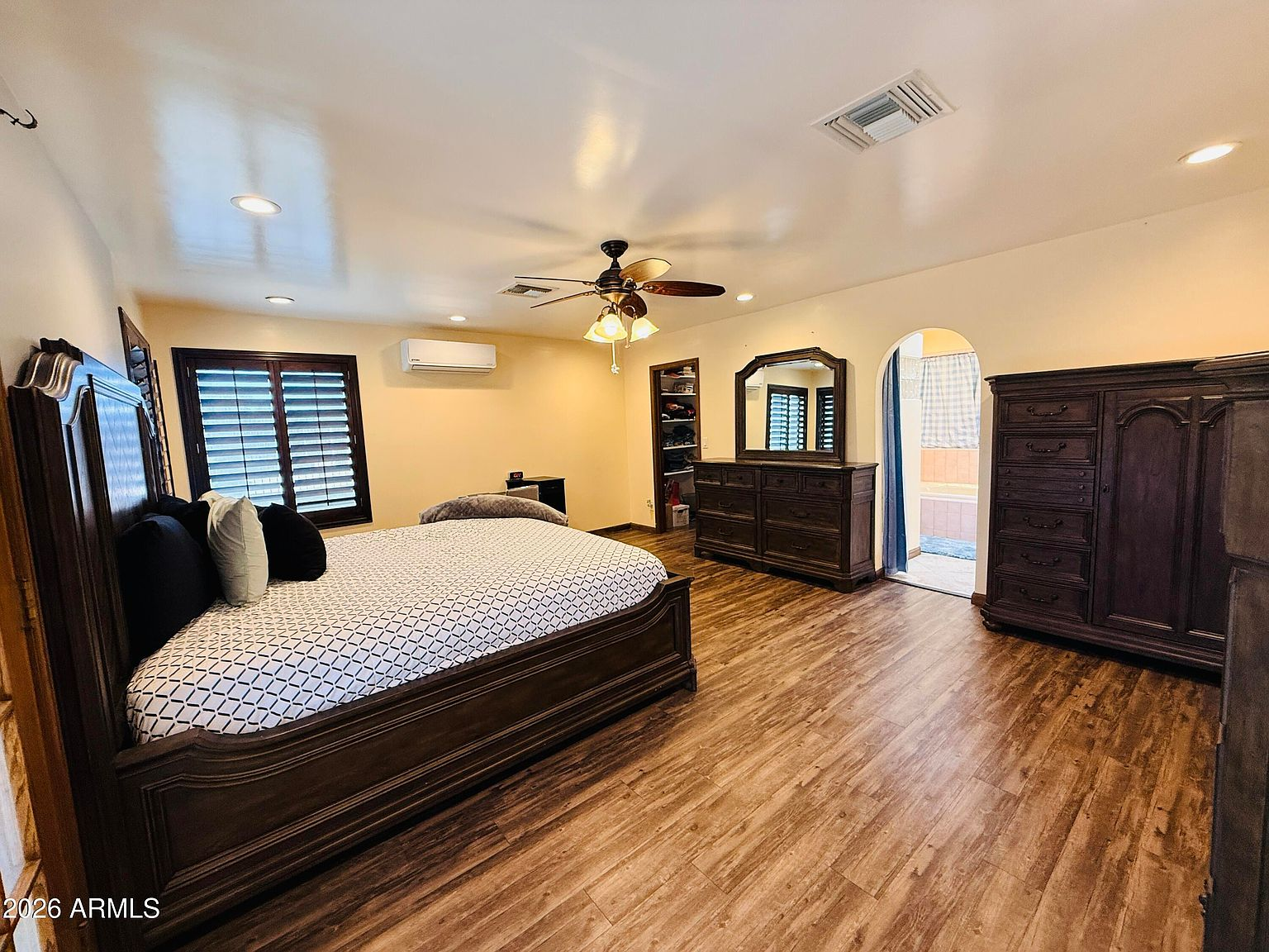 Master bedroom with arched doorway and dark wood furniture