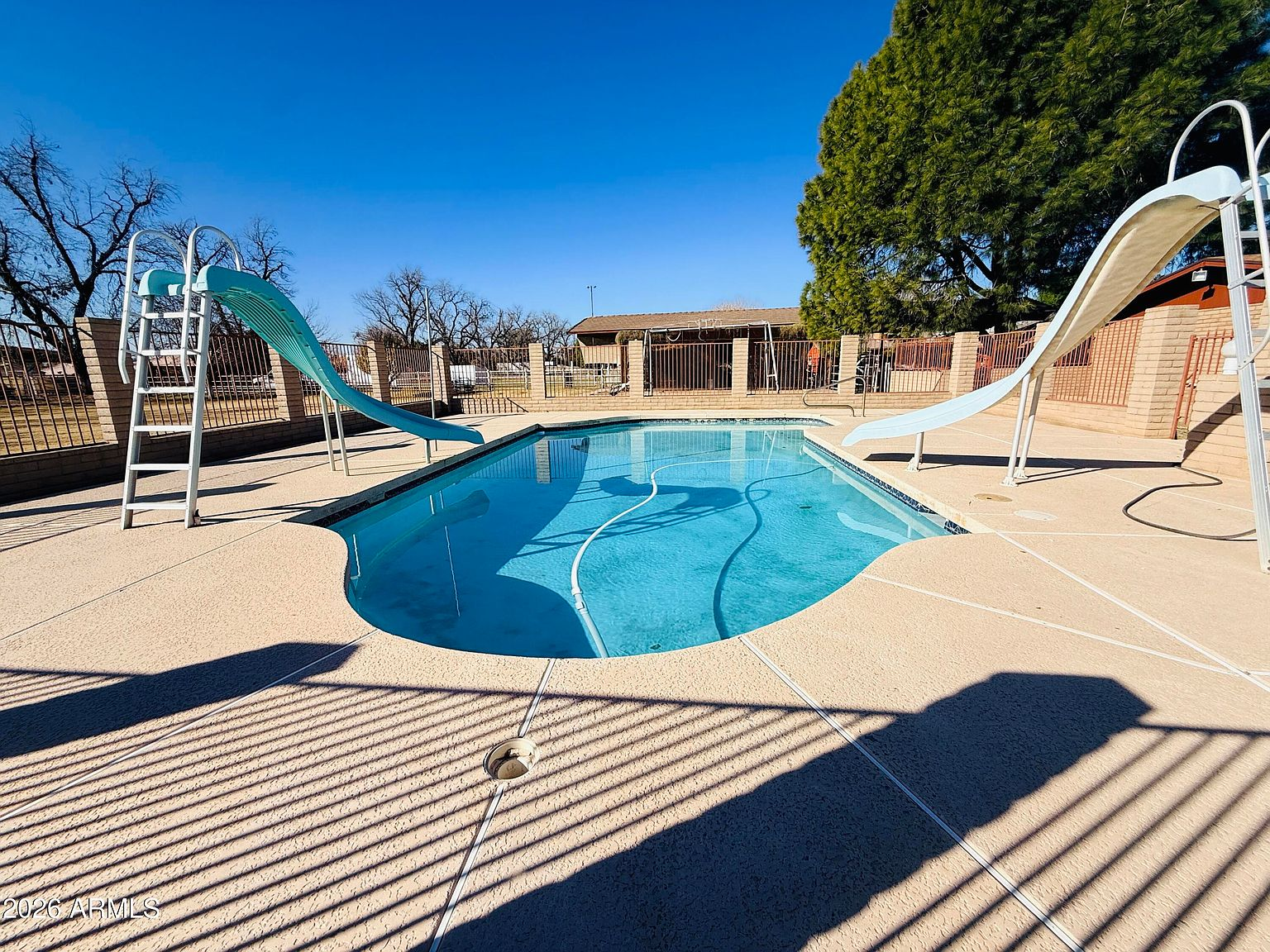 Fenced backyard swimming pool with slides