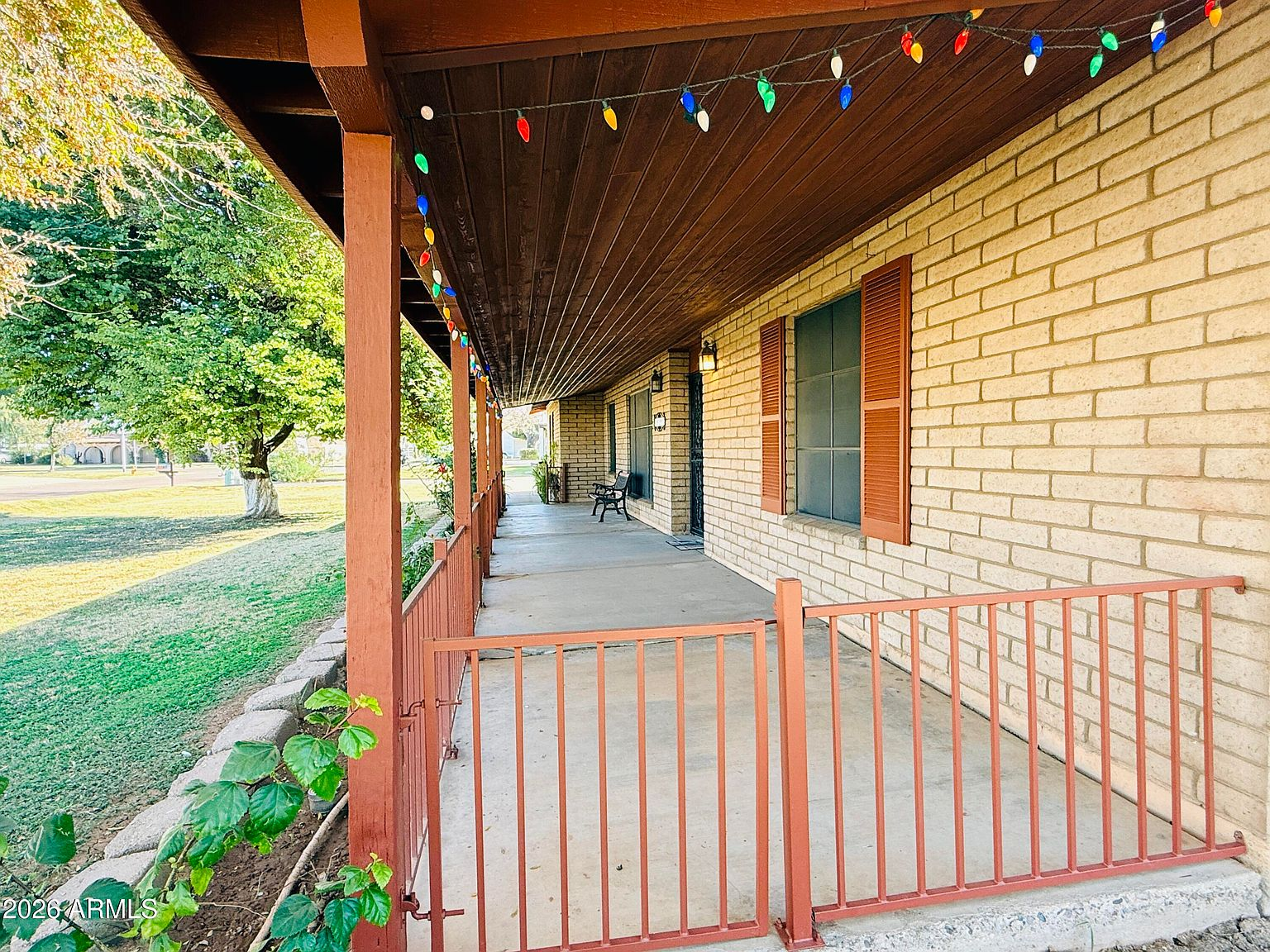 Covered front porch with brick facade and shutters
