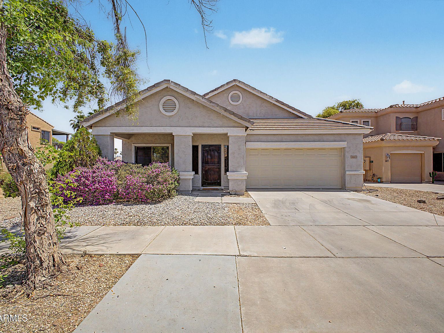 Front facade from the sidewalk with two-car garage and desert landscaping
