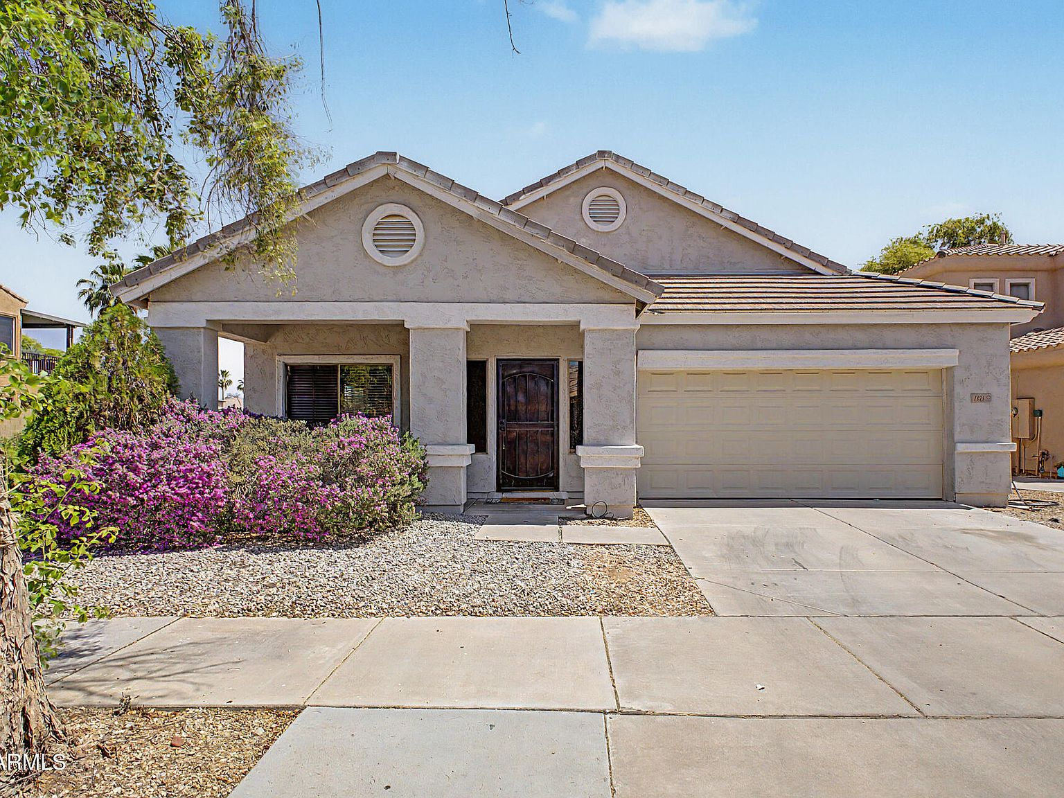 Welcoming single-story ranch home with cream stucco and desert landscaping in Goodyear, Arizona