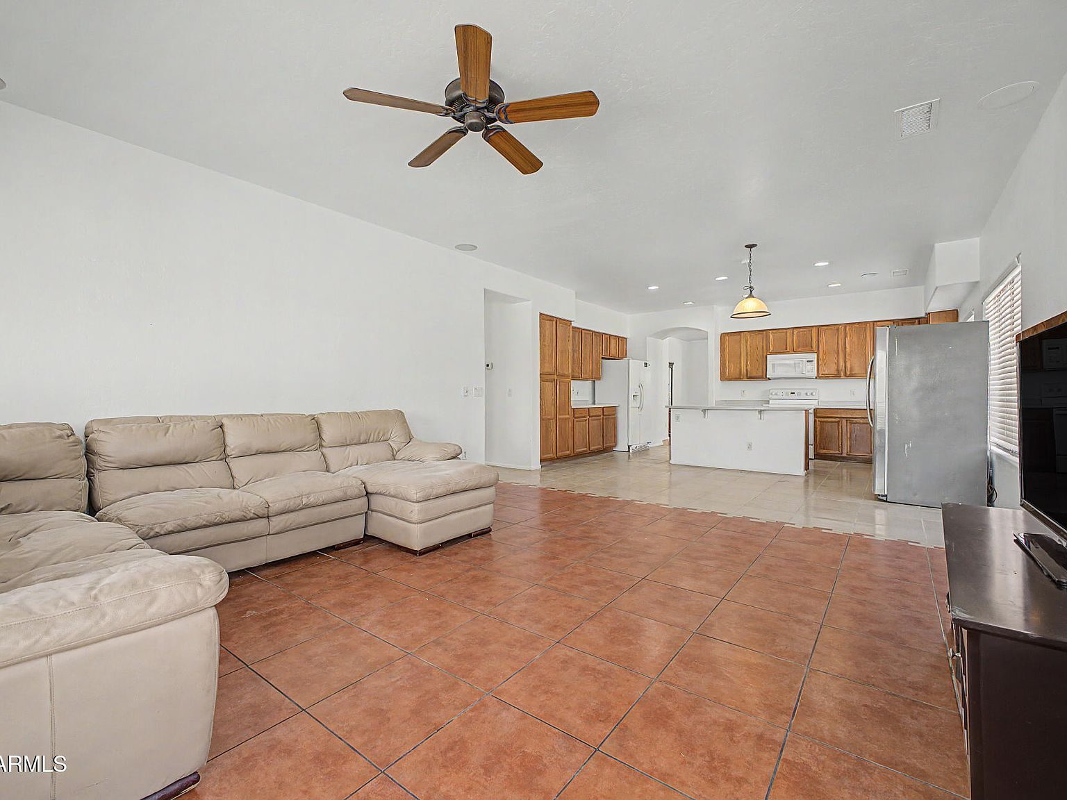 Open-concept living room with tile flooring flowing toward the kitchen