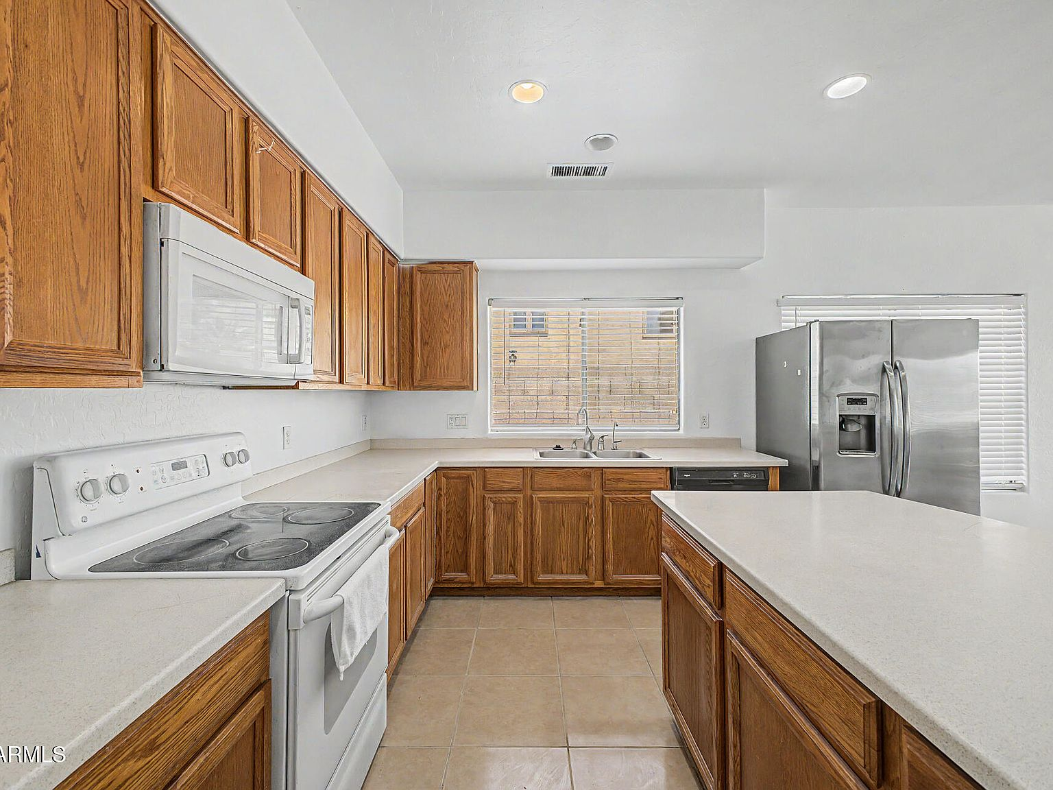 Kitchen with oak cabinetry, refinished countertops, central island, and built-in appliances