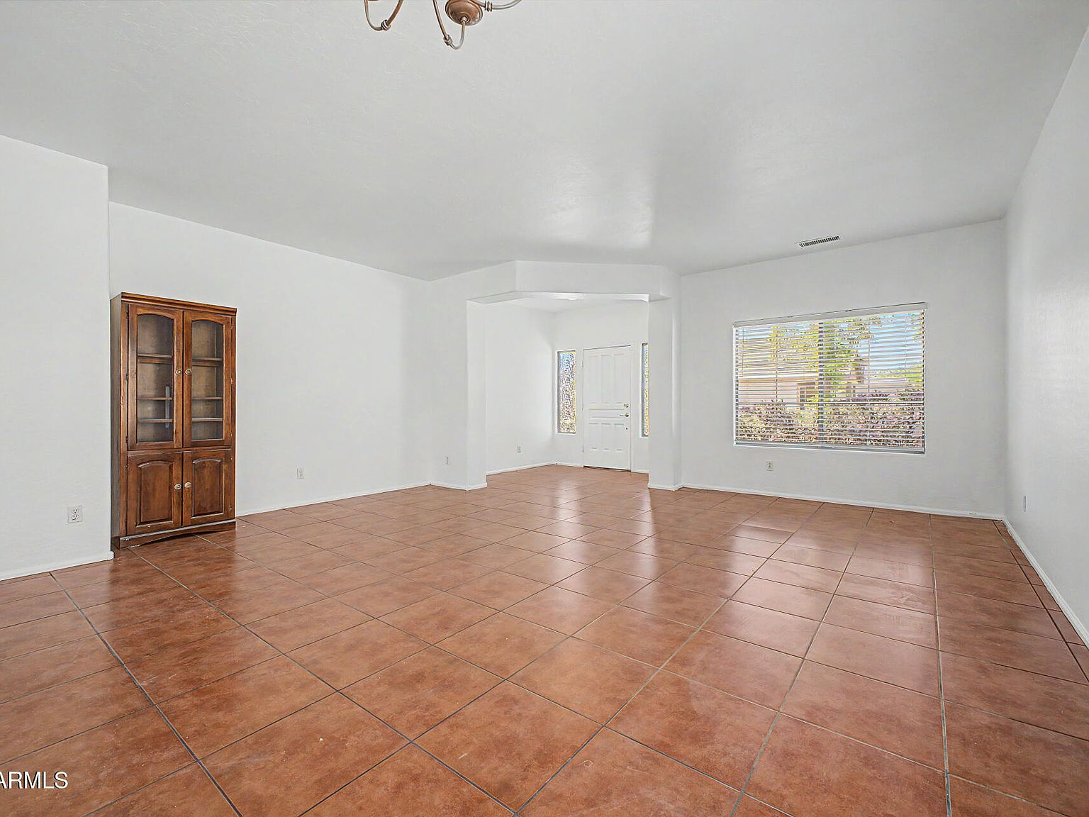 Formal living and dining area with terracotta tile flooring and natural light from large windows