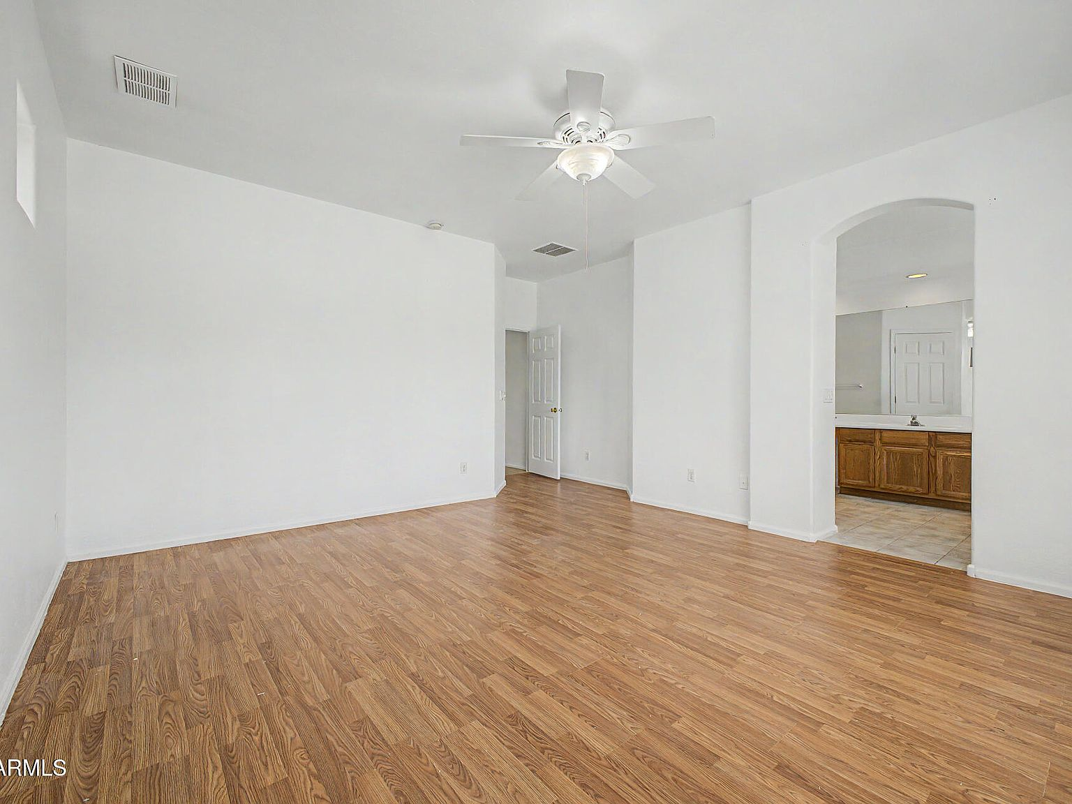 Primary bedroom with wood-look flooring and natural light