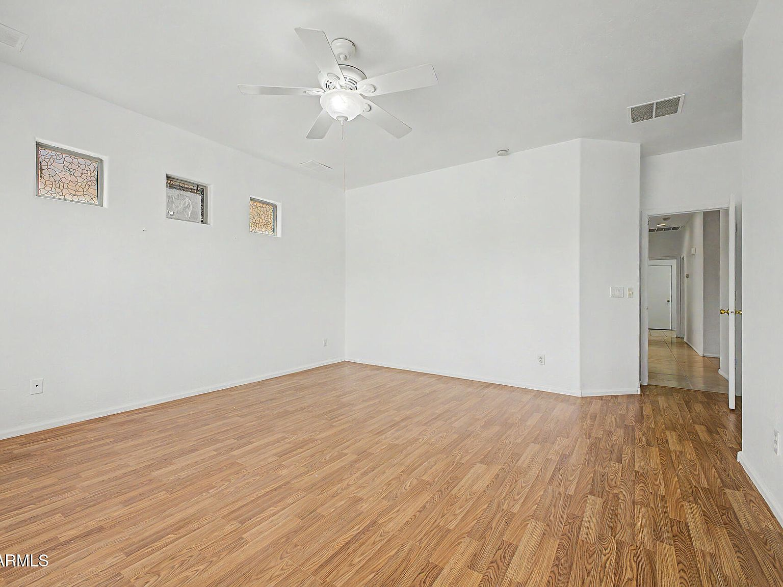 Bedroom with wood-look flooring and triple high-set windows
