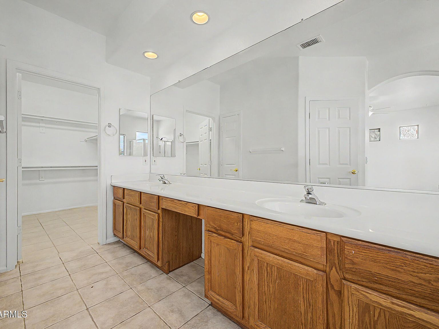 Primary bathroom with dual vanity, walk-in closet, and tile flooring