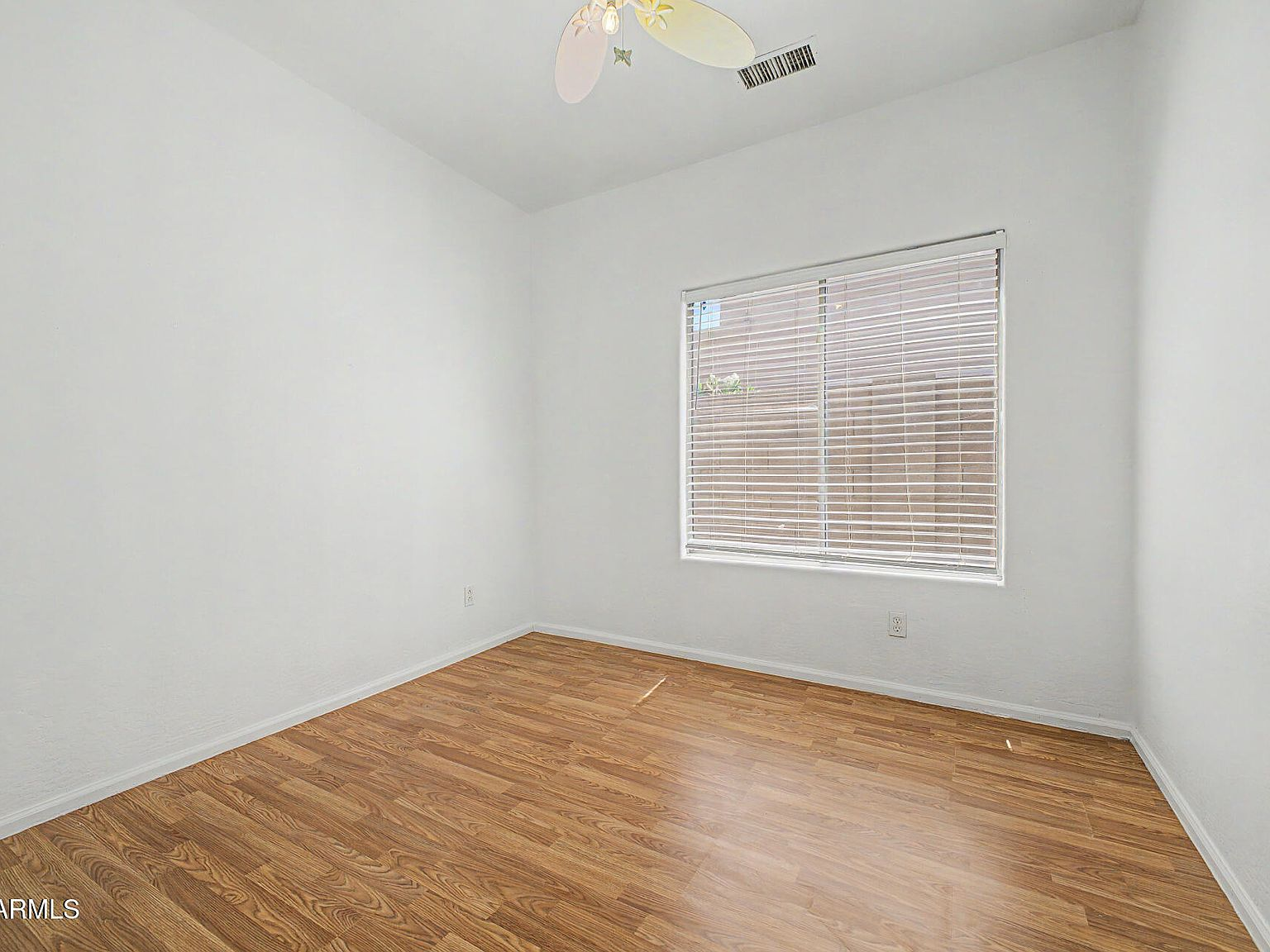 Bedroom with wood-look flooring and window with blinds