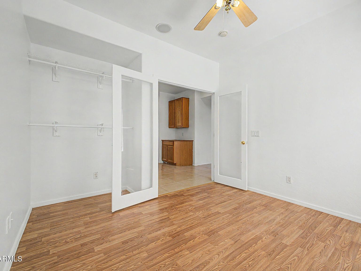 Bedroom or office with wood-look flooring and glass-panel closet doors