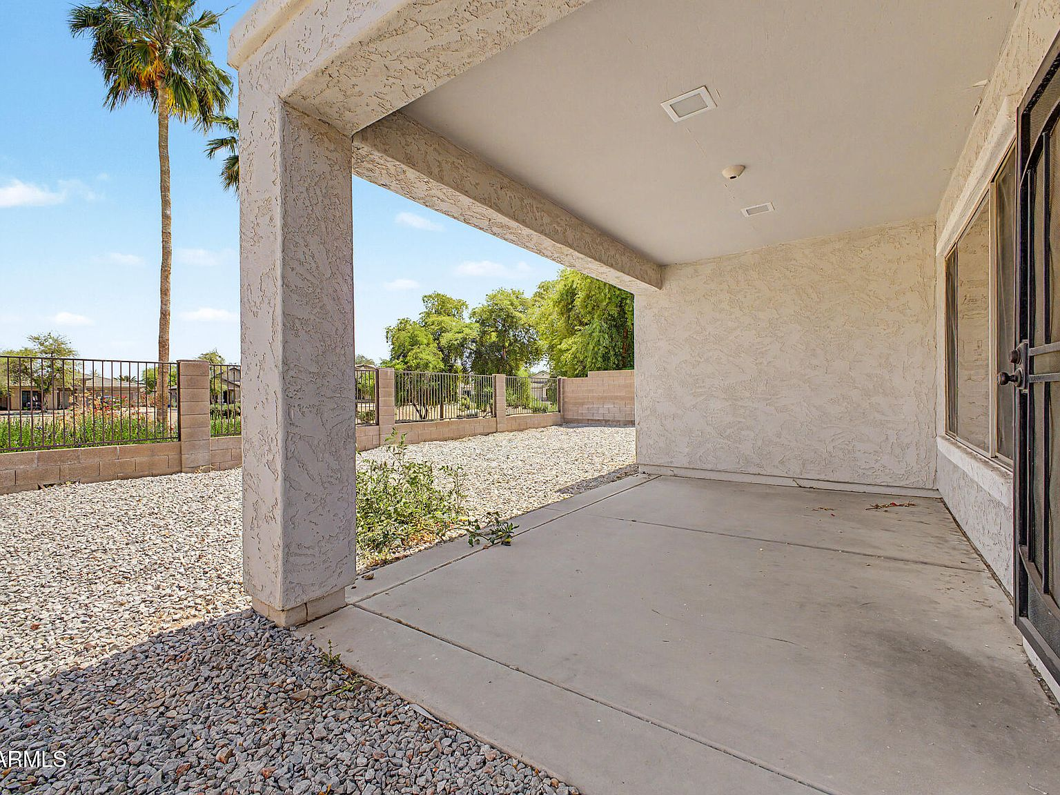 Covered back patio with concrete slab and desert landscaping beyond