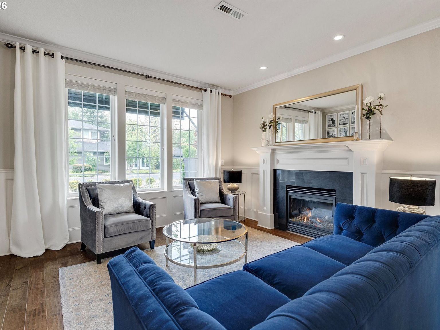 Light-filled living room featuring clean wainscoting and fireplace
