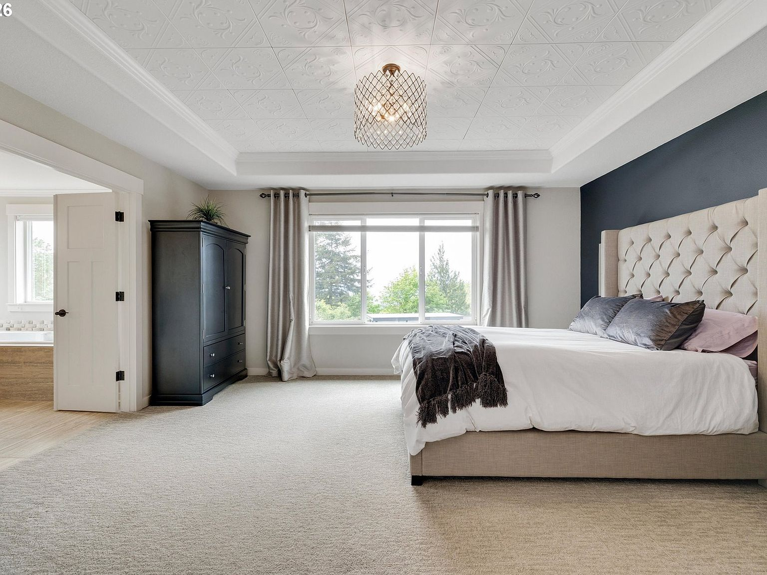 Upper primary suite with tray ceilings, navy accent wall and valley views