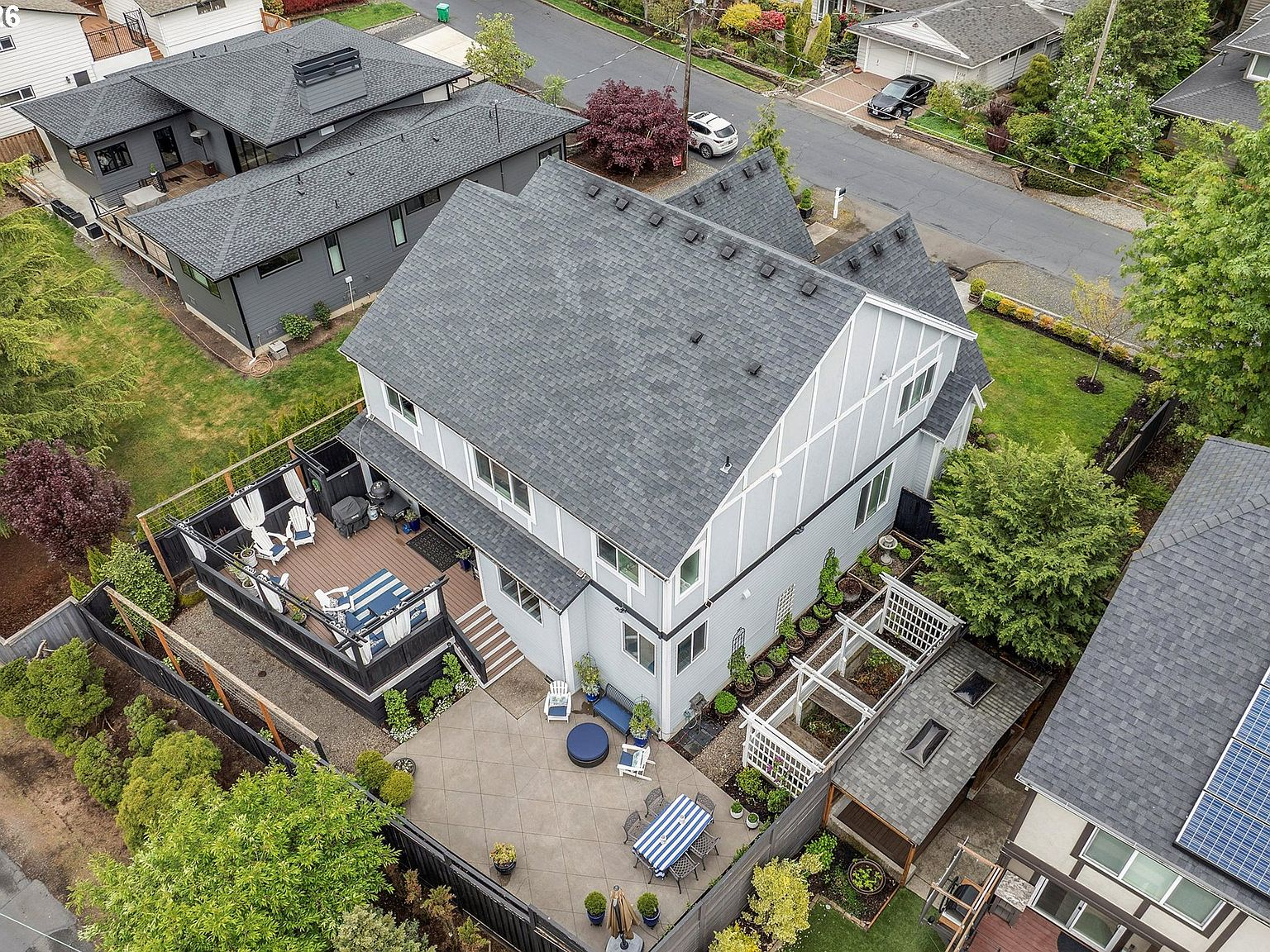 High-angle drone perspective of the backyard layout, elevated deck, and modern Tudor exterior