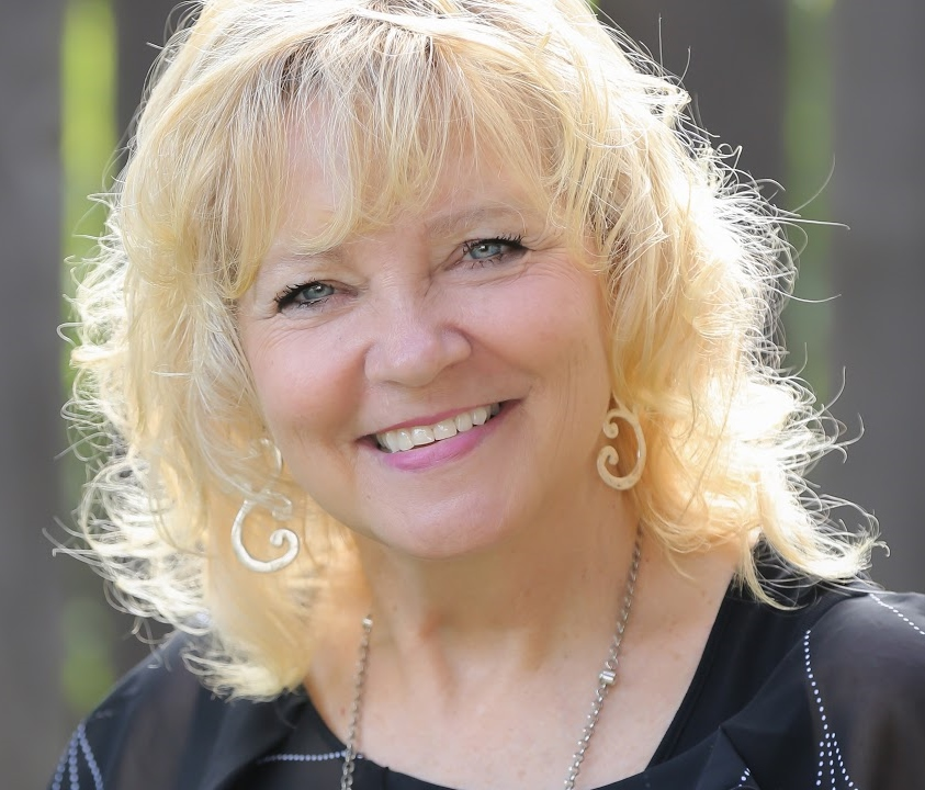 Warm, professional headshot of Carol Layman, smiling real estate agent with wavy blonde hair
