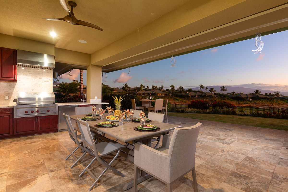 Wide-angle view of the covered dining deck at twilight, showing the complete built-in barbecue station with stainless steel hood.