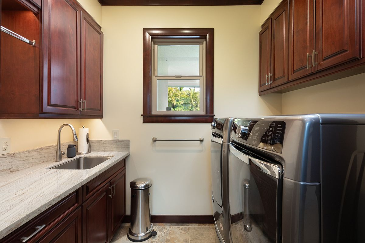 Pristine laundry and home utility room with granite workspaces.