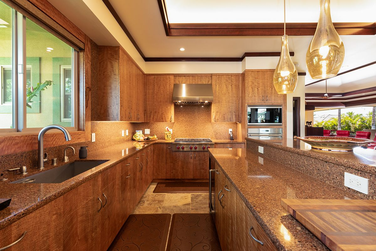 Spacious designer kitchen featuring detailed natural wood cabinetry, a massive warm-toned granite prep island, and premium appliances.