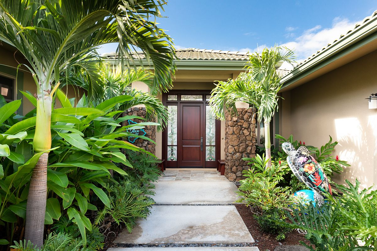 Elegant front facade and entryway pathway bordered by lush native Hawaiian plants and structured concrete pavers.