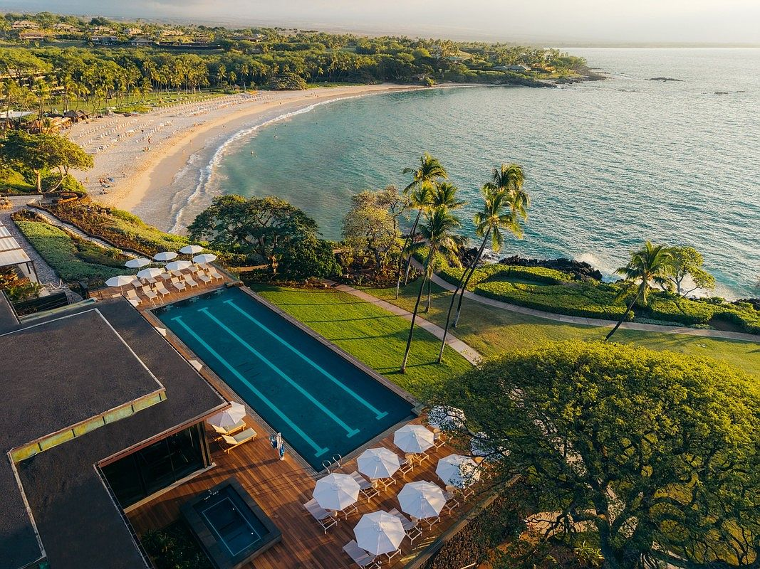 High-angle aerial photograph of the pristine resort sandy beach cove and beachfront pool