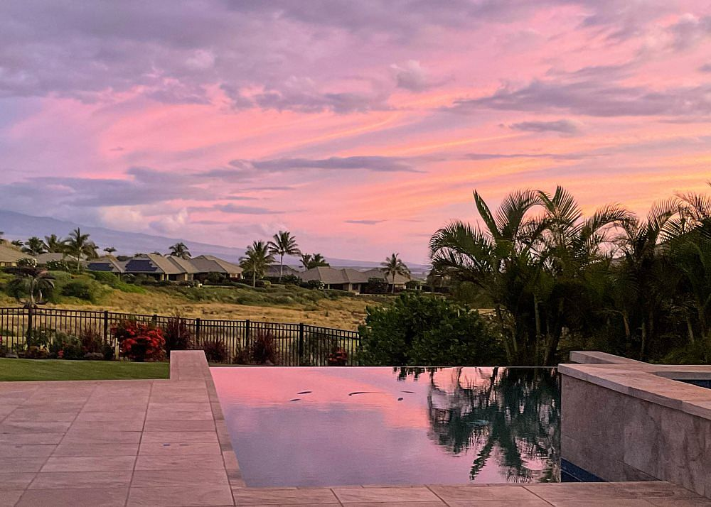 Sunset reflection in the still infinity pool overlooking the oceanfront resort