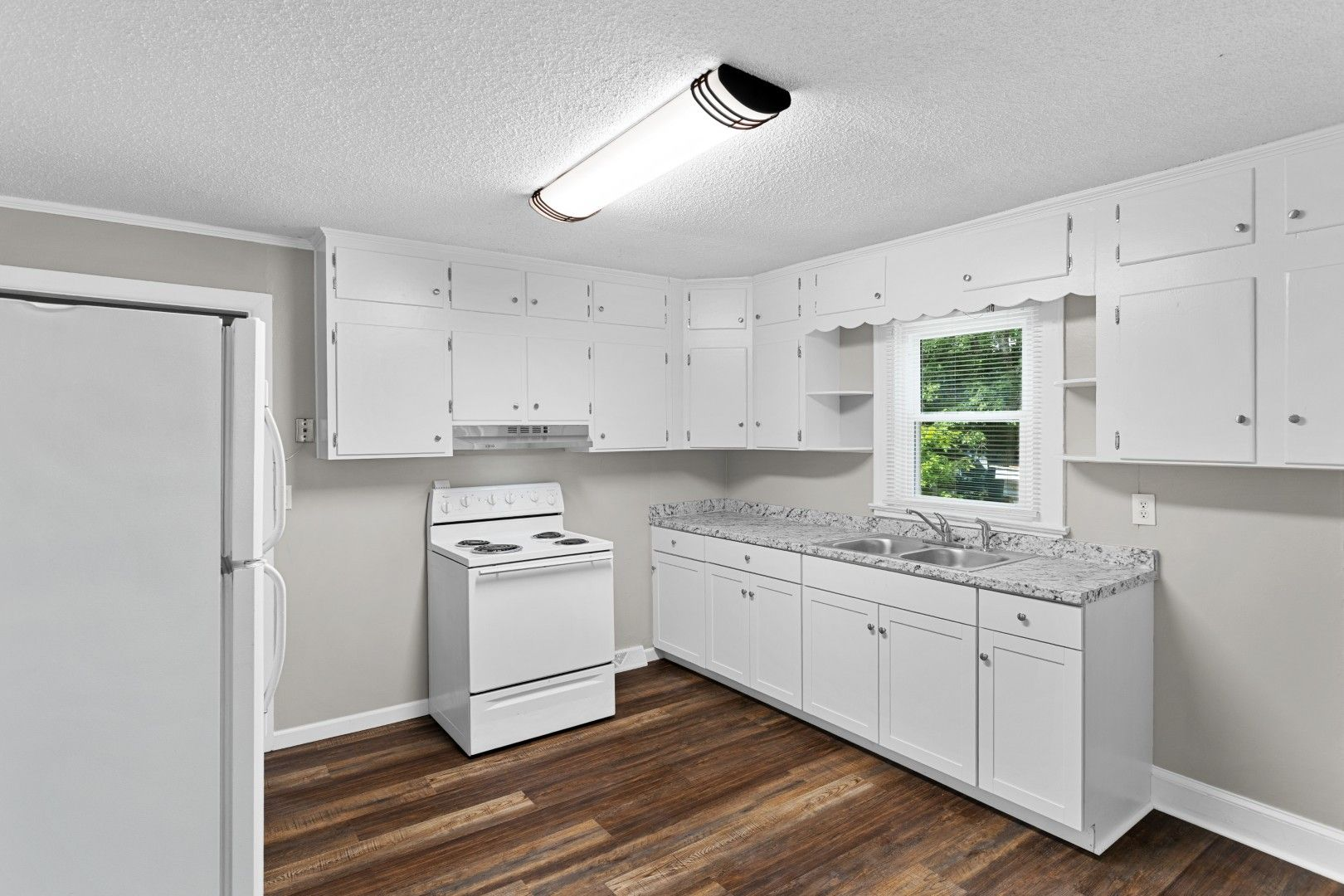 A meticulously updated kitchen featuring clean white cabinetry and modern white appliances
