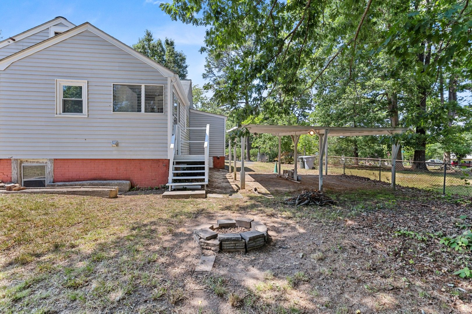 Wide-angle level quarter-acre backyard with a fire pit and detached carport