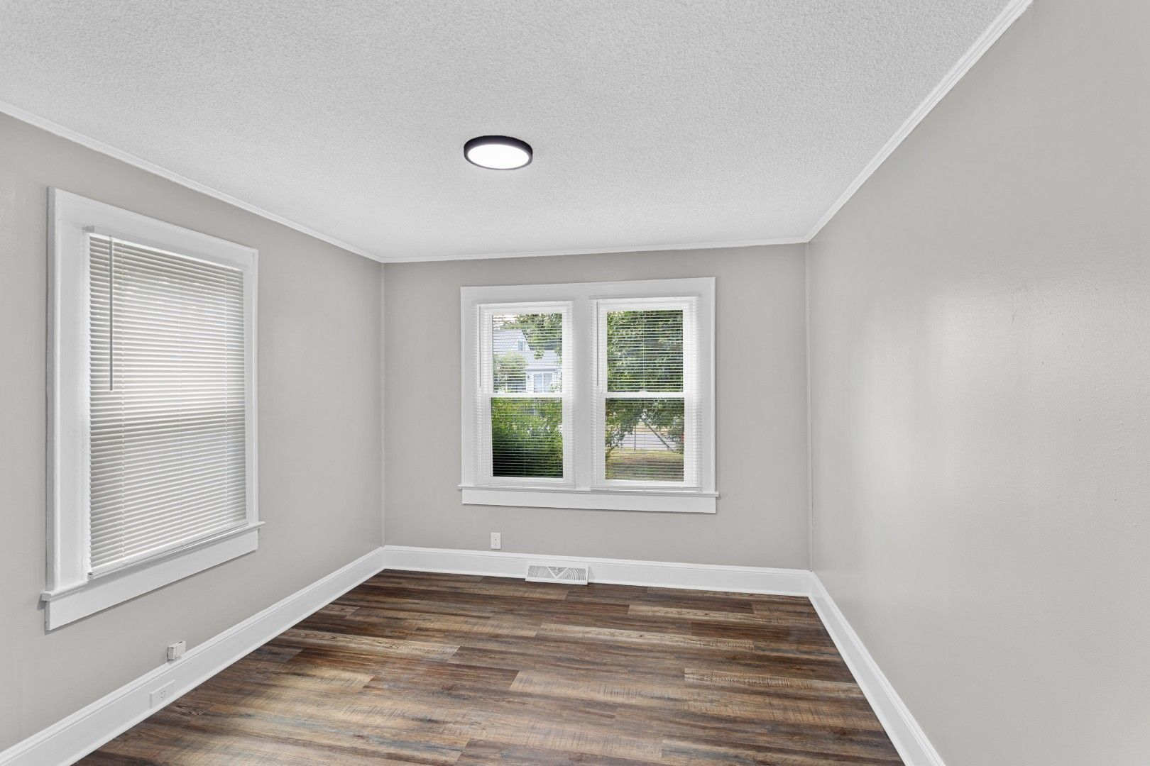 Bright and open secondary bedroom highlighting wood-look vinyl plank flooring and double windows