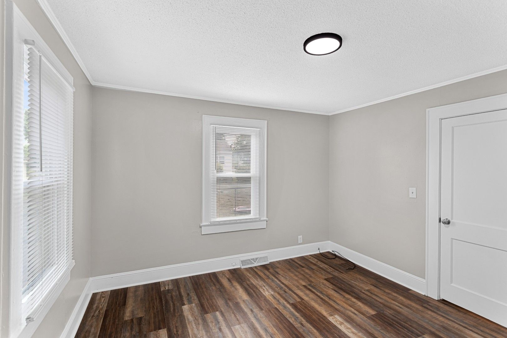 Second empty bedroom with clean grey painted walls and wooden-style vinyl flooring