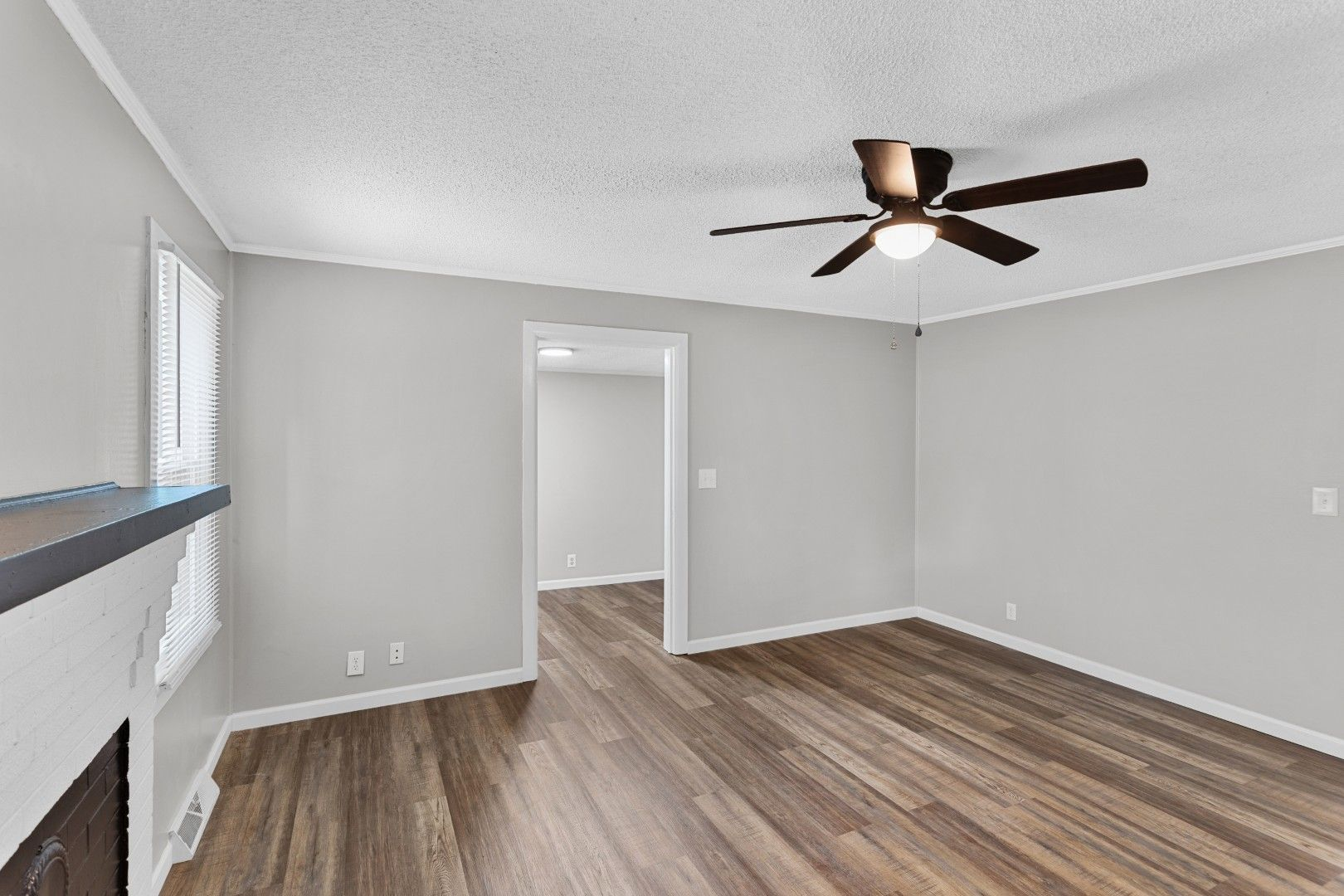 Another perspective of the spacious living room highlighting the white decorative-only fireplace mantel
