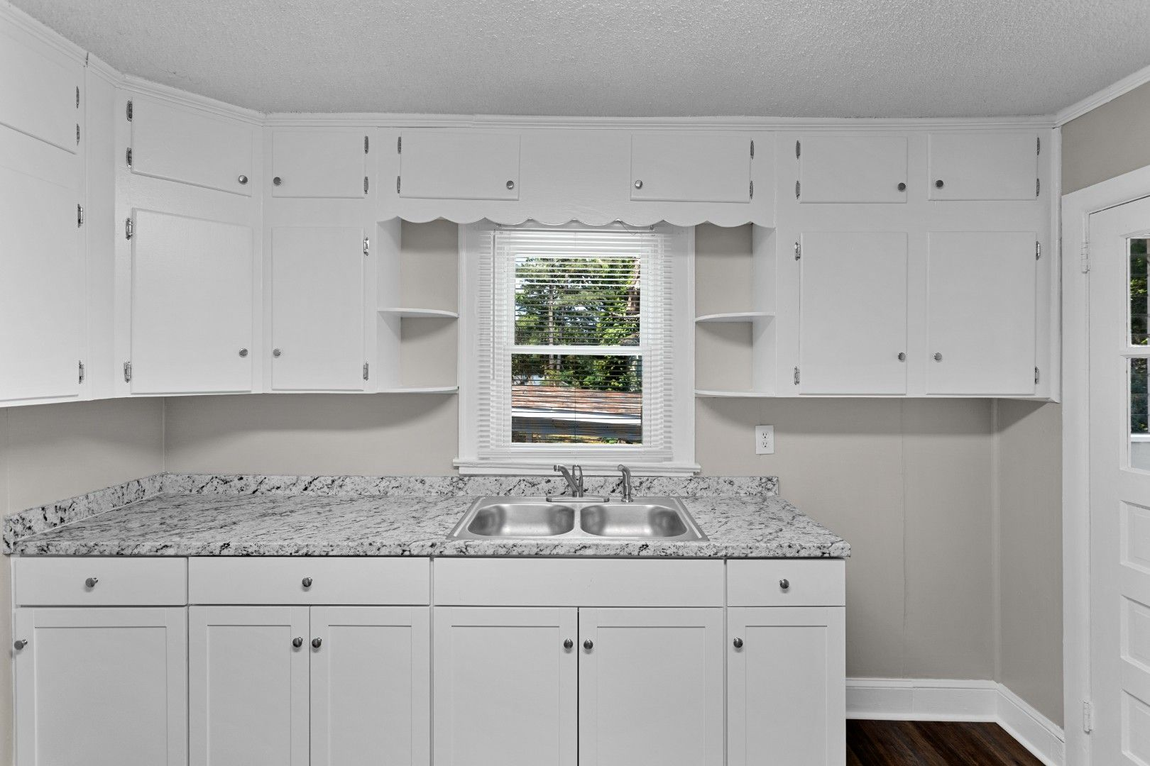 Kitchen vanity sink area with scalloped trim and modern faucet looking towards window